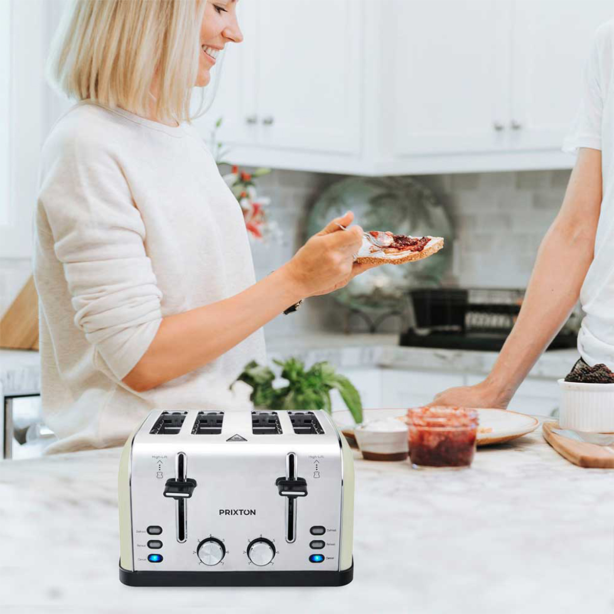 Kobieta opieka chleb z dżemem obok tostera. Mężczyzna stoi obok niej.