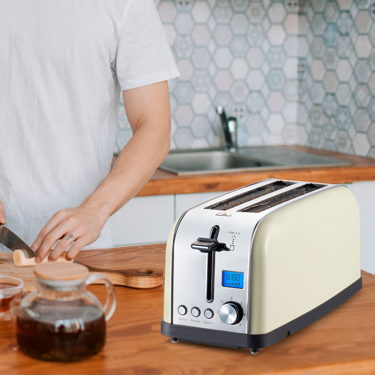 Kremowy toster na drewnianej powierzchni. Osoba kroi coś na desce do krojenia.