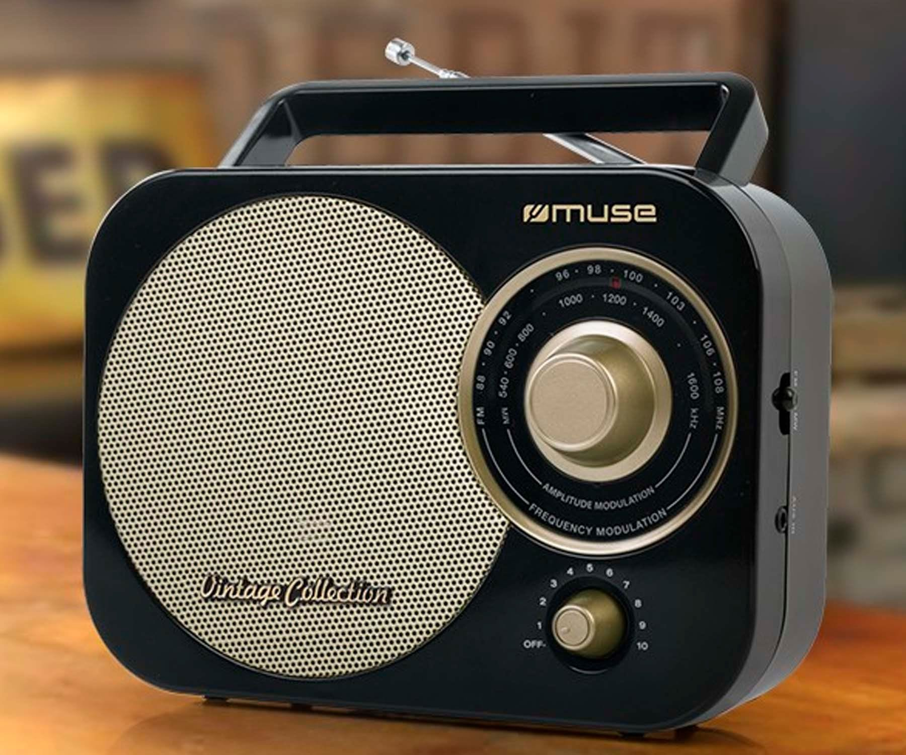 Czarno-złote radio w stylu vintage z uchwytem, pokrętłem i głośnikiem na drewnianej powierzchni.