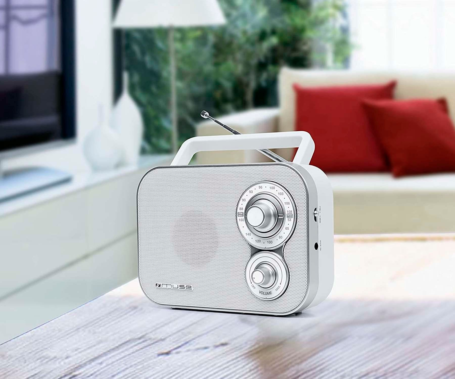 Białe radio z uchwytem na drewnianym stole, z rozmytym tłem.