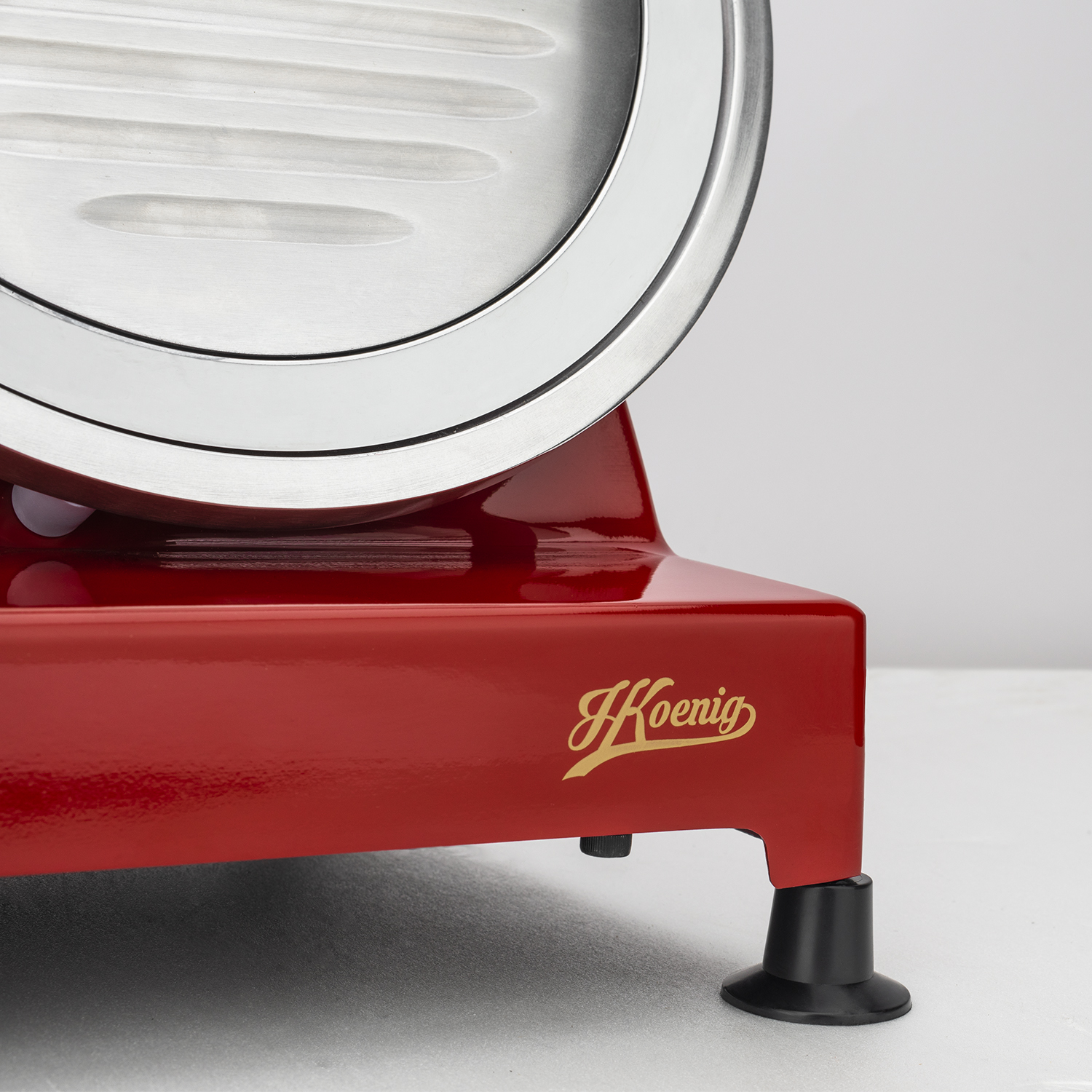 Czerwona krajalnica do mięsa ze srebrnym ostrzem. Ma złoty napis Koenig.