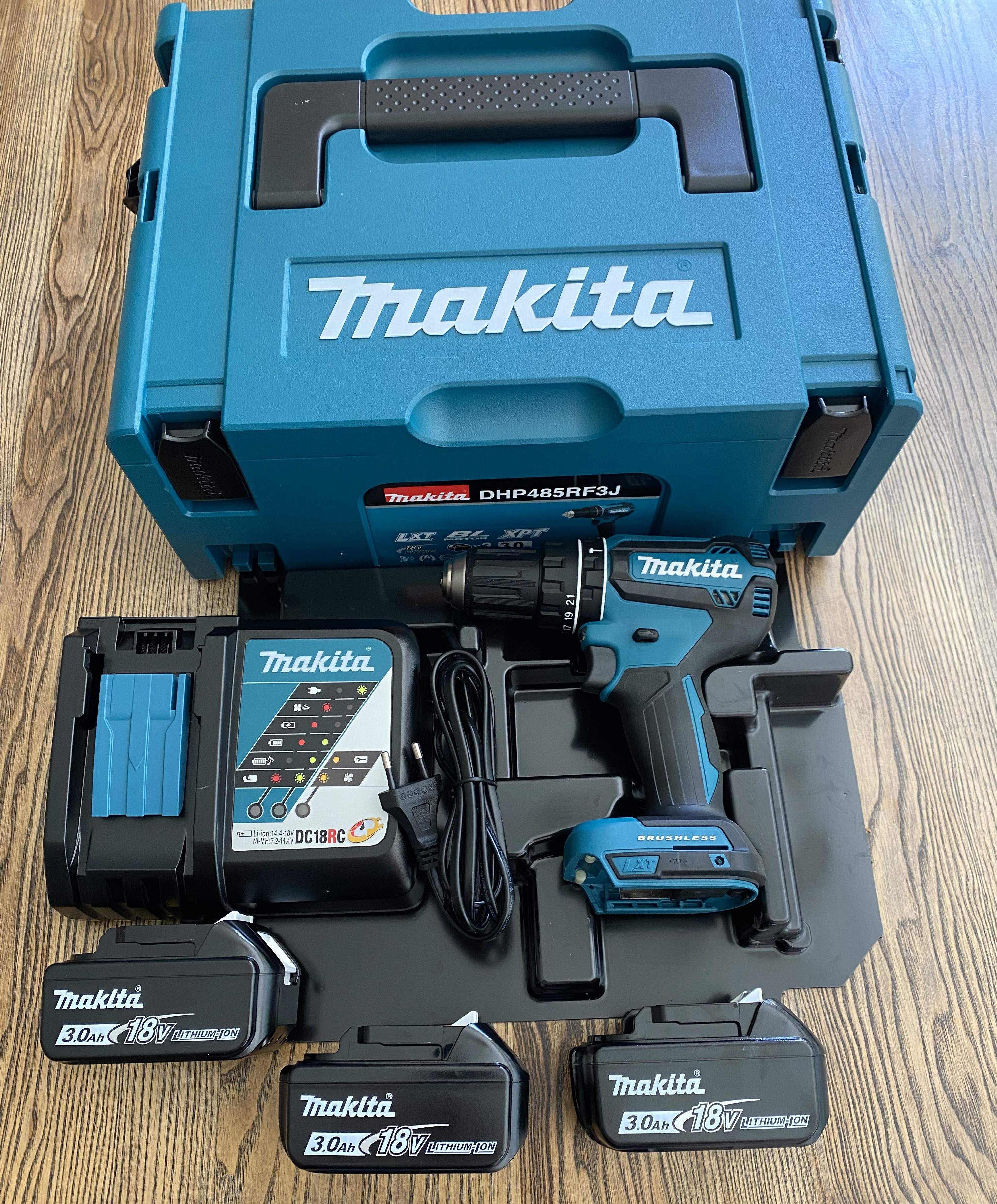 Eine türkisfarbene Werkzeugkiste. Darin befinden sich Werkzeuge, darunter eine Bohrmaschine und Batterien.