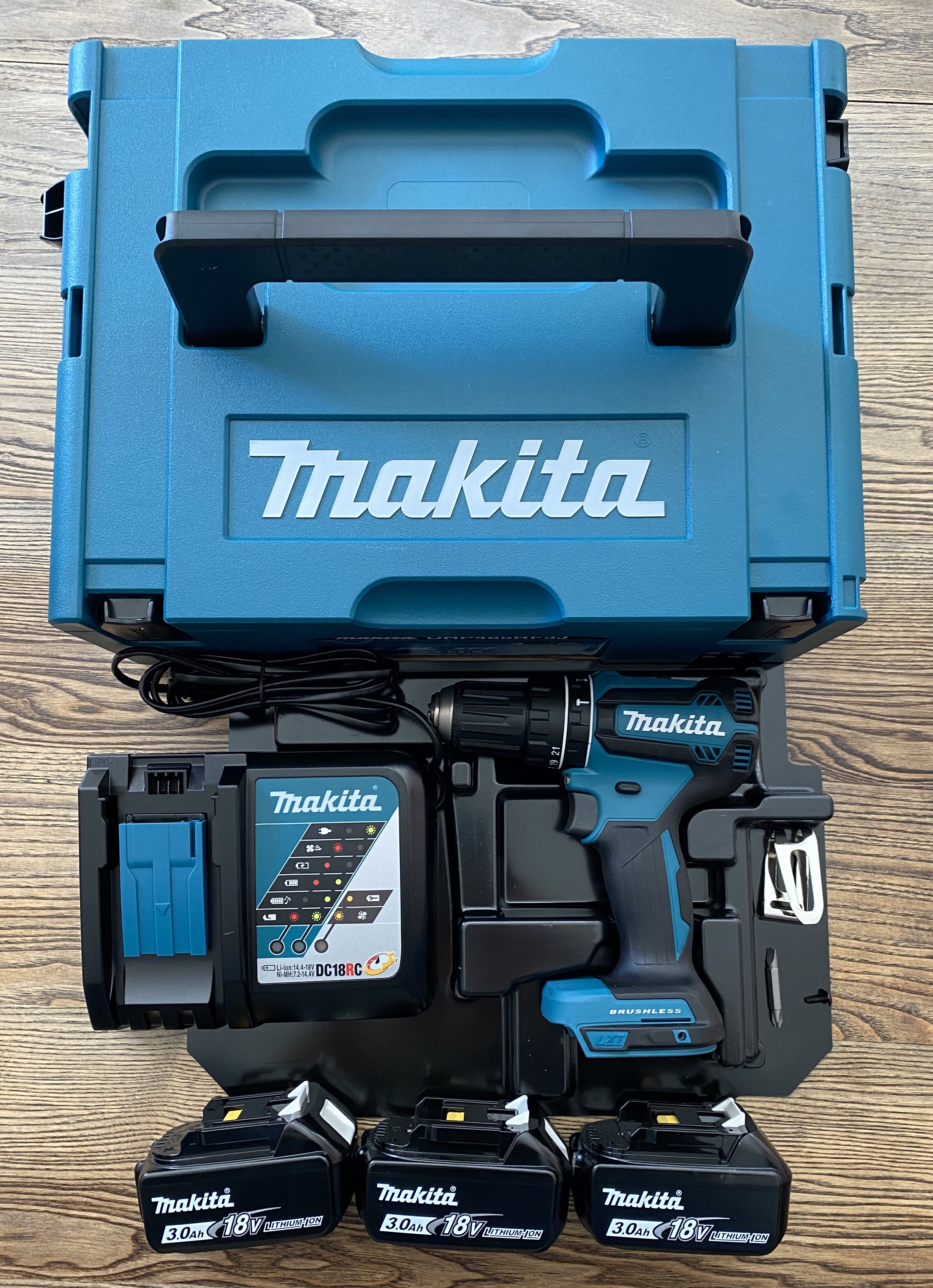 Makita Werkzeugsatz im Koffer. Enthält Bohrmaschine, Akkus und Ladegerät auf Holz.