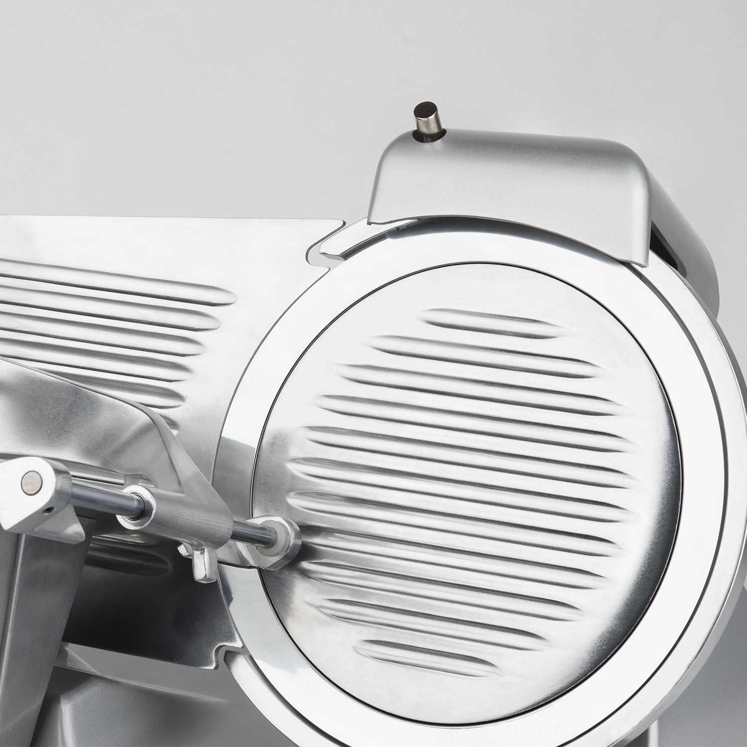 Błyszcząca, srebrna, elektryczna krajalnica do mięsa z dużym okrągłym ostrzem i uchwytem.