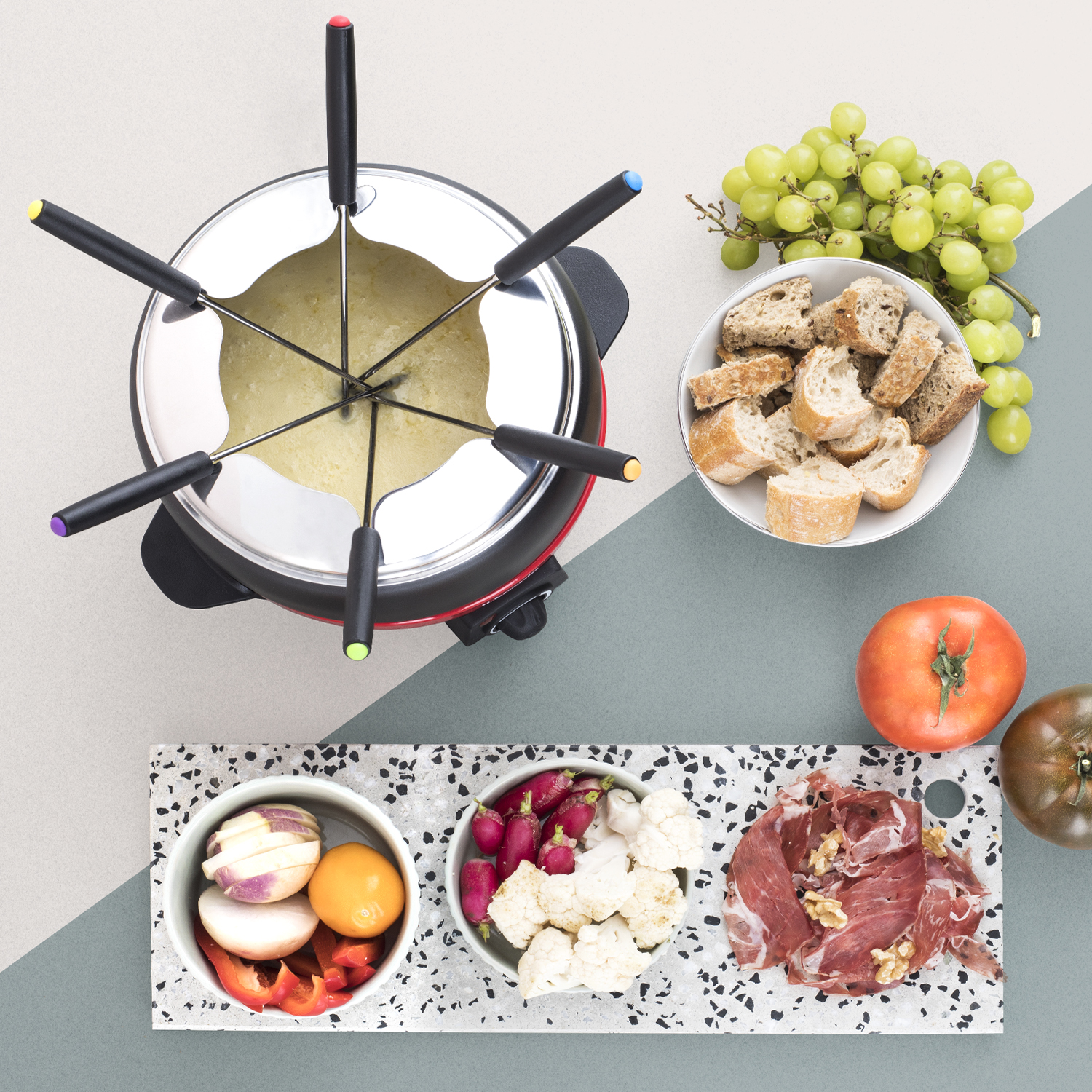 Zestaw do fondue z miskami jedzenia i szpikulcami. Tło to mieszanka szarości, bieli i błękitu.