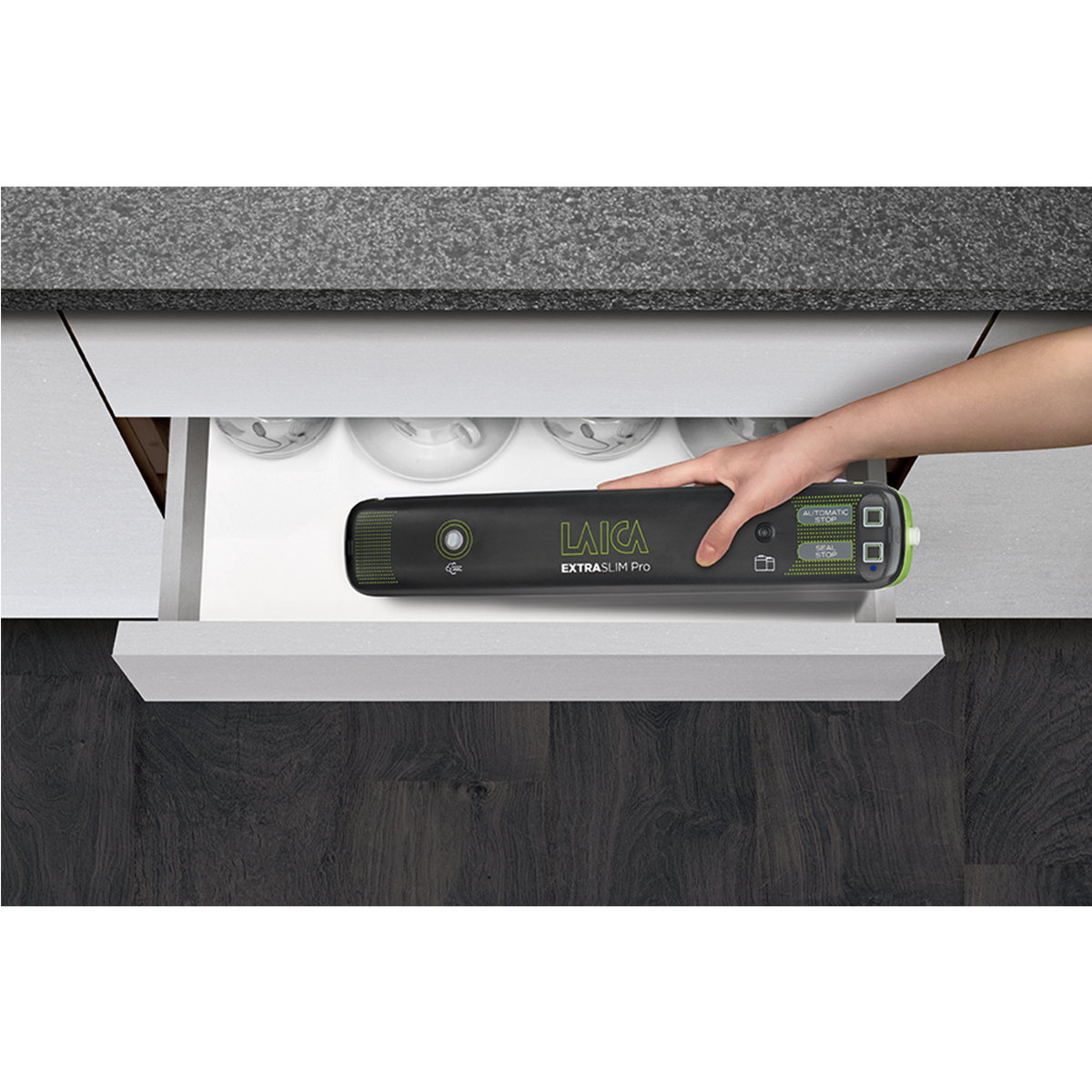 Ręka wysuwa czarną zgrzewarkę próżniową z szuflady. Tekst mówi LAICA EXTRASLIM Pro.