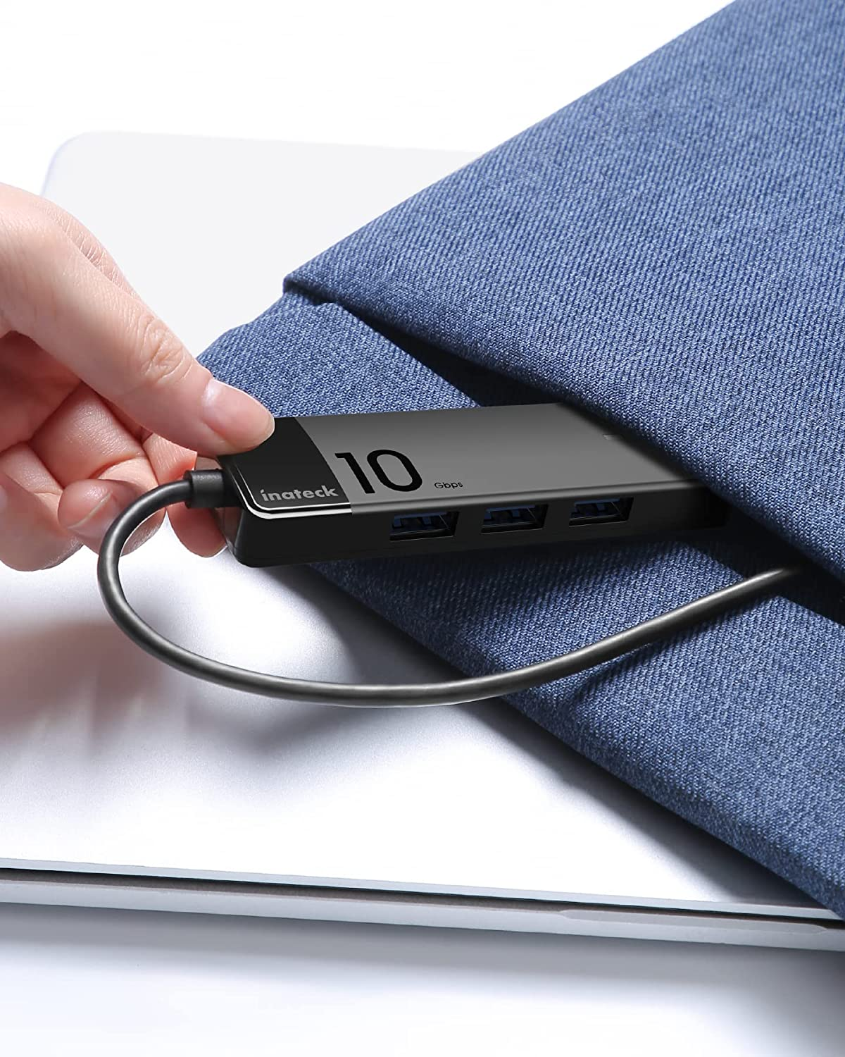 Eine Person hält einen USB-Hub, der an einen Laptop in einem blauen Beutel angeschlossen ist.