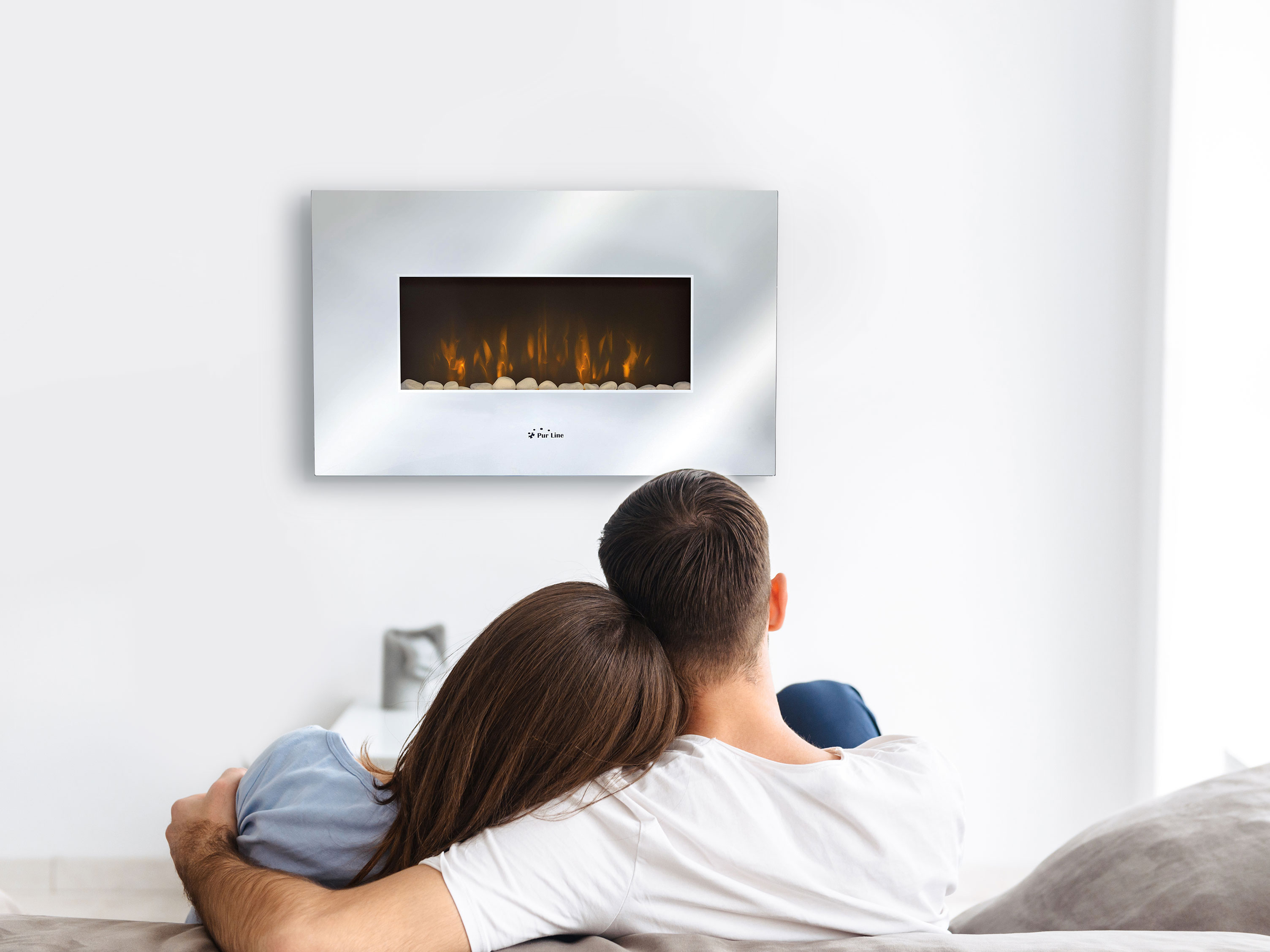 Ein Paar betrachtet einen an der Wand befestigten elektrischen Kamin mit künstlichen Flammen.
