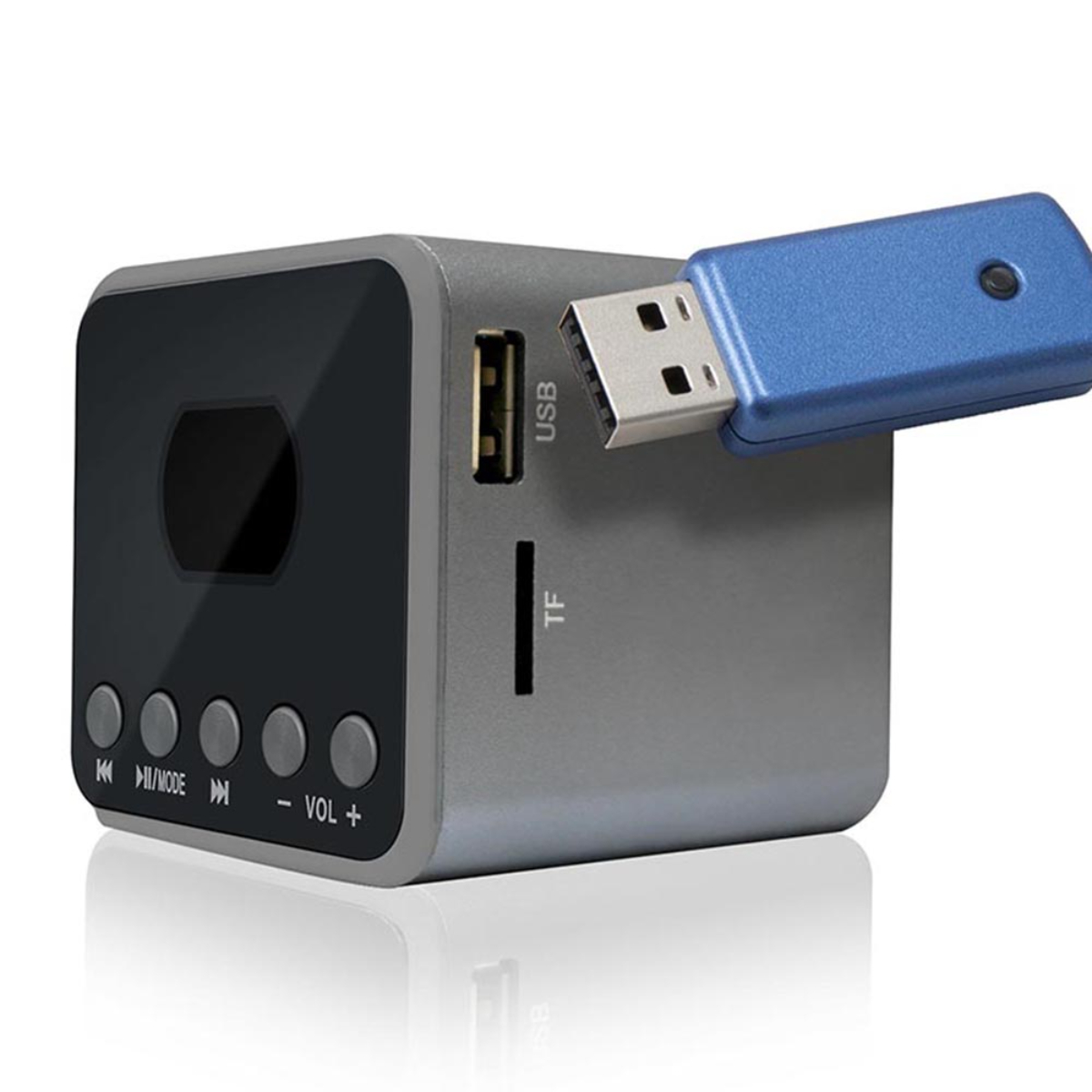 Altavoz plateado en forma de cubo con puerto USB y memoria USB azul insertada.