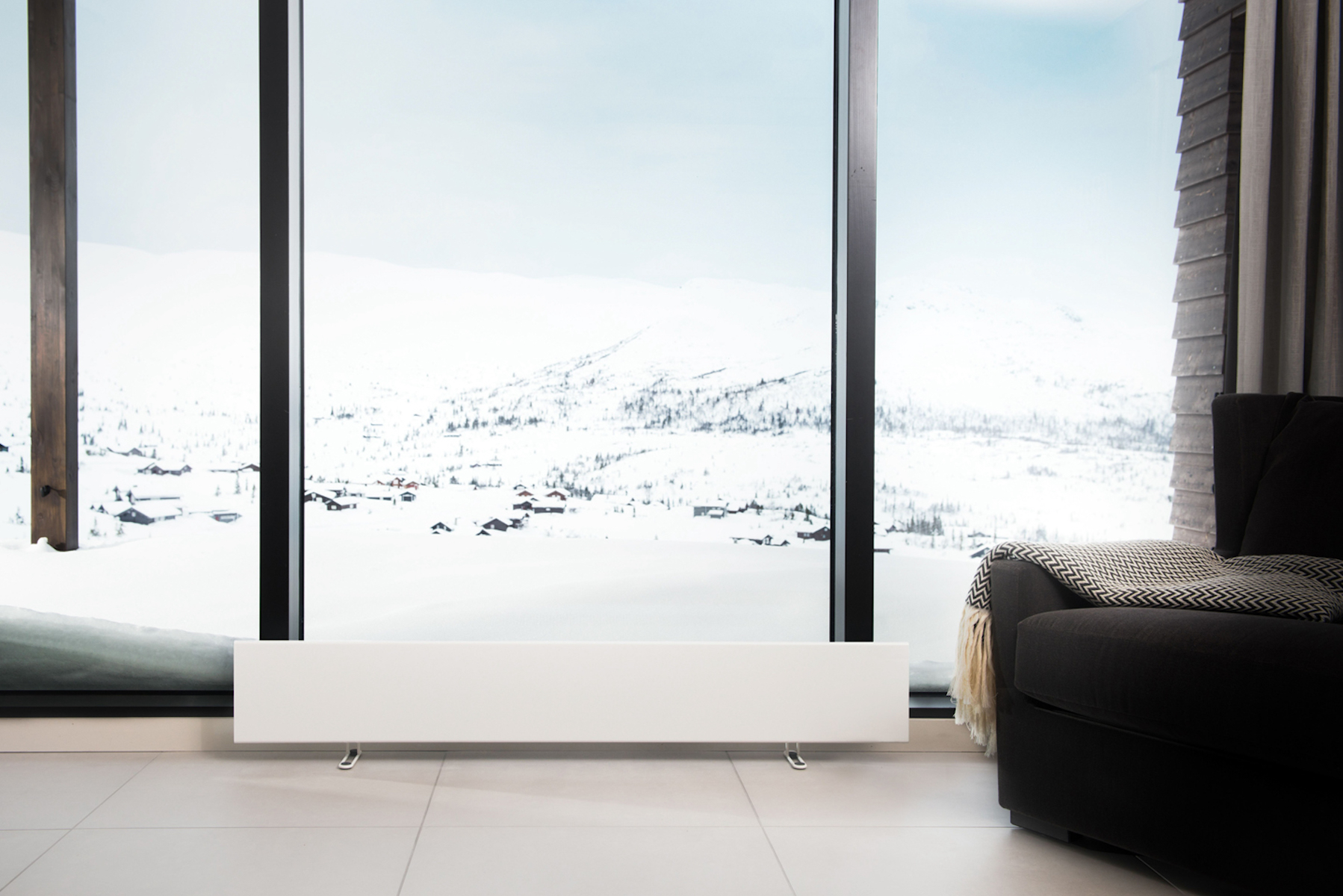 Una finestra con vista su un paesaggio innevato. Sotto la finestra c'è un termosifone bianco.