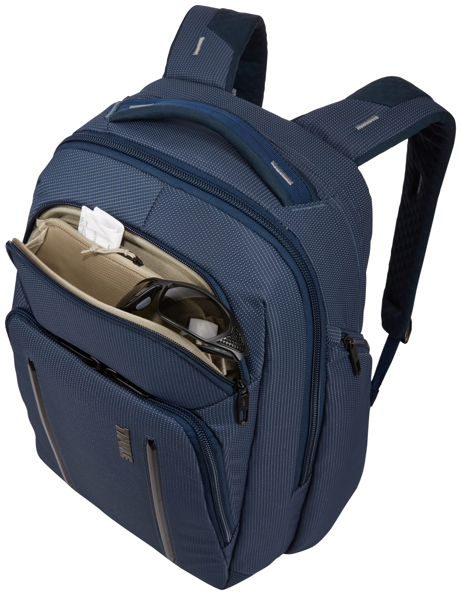 Blauer Rucksack, offen, mit Sonnenbrille und anderen Gegenständen darin. Weißer Hintergrund.