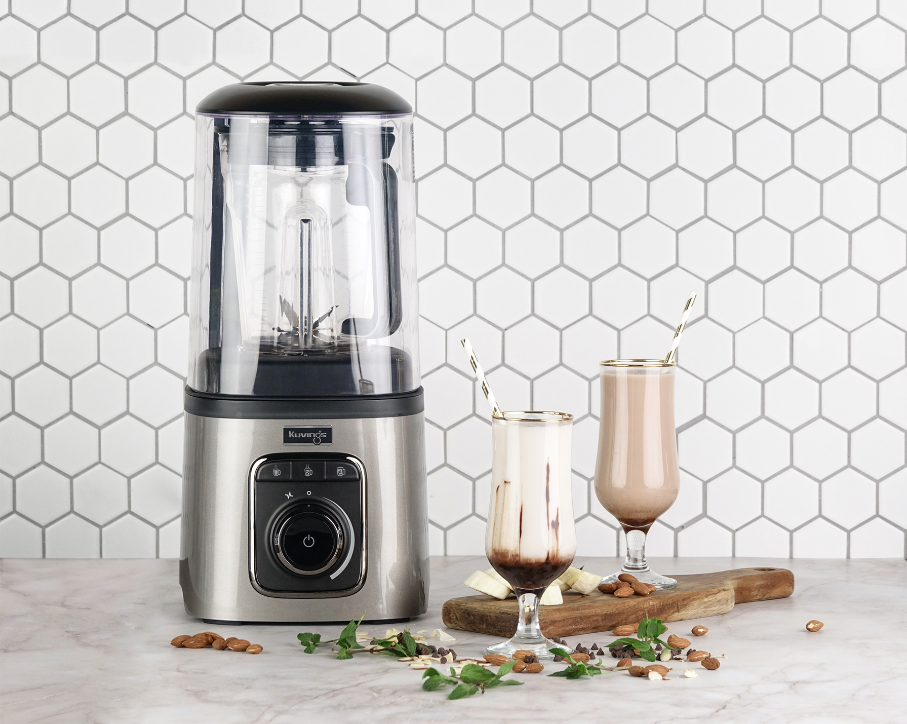 Blender z dwoma szklankami koktajli. Wokół blendera są orzechy i owoce.