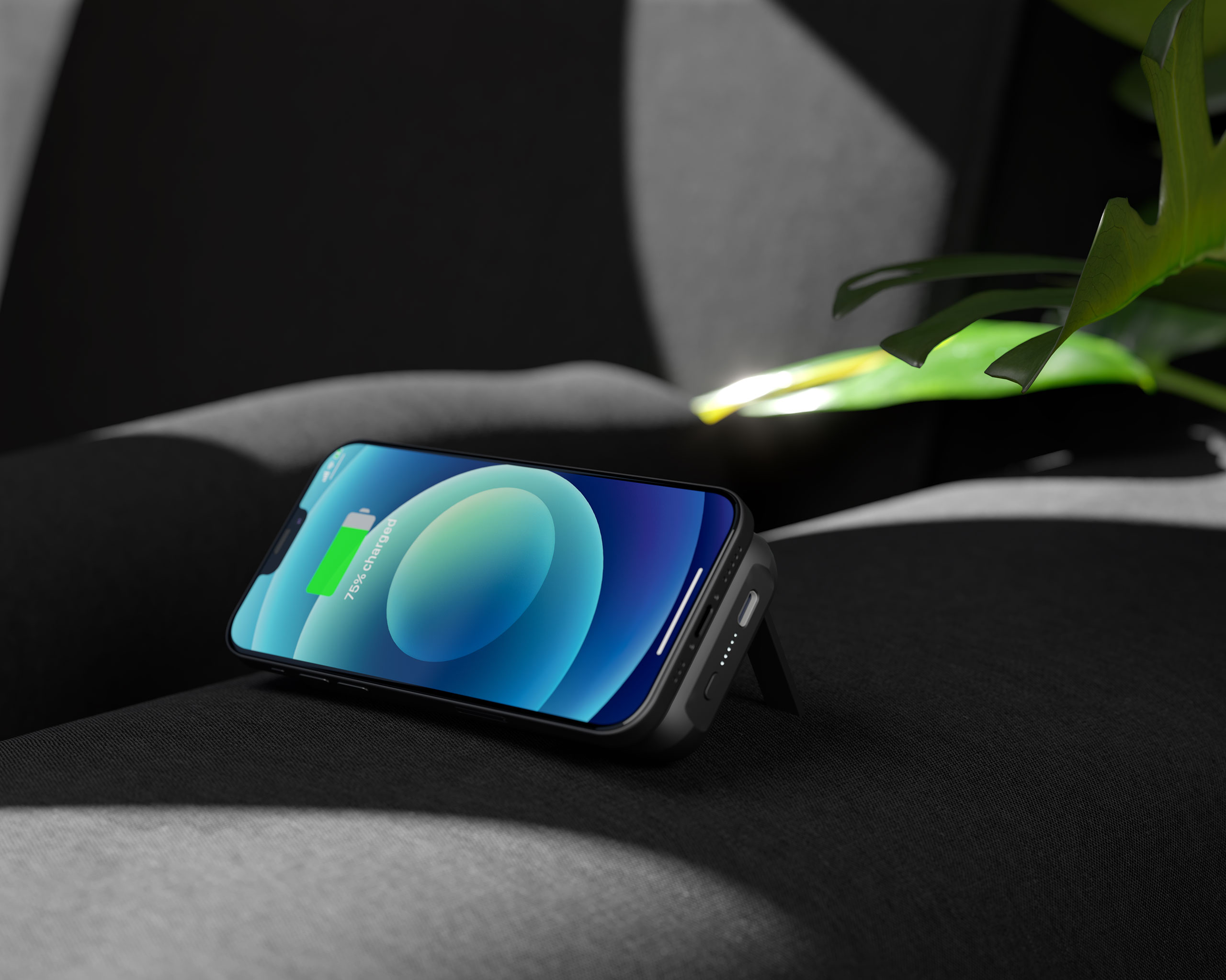 Un telefono su un caricatore wireless su un divano scuro con una pianta. Il telefono mostra la batteria.
