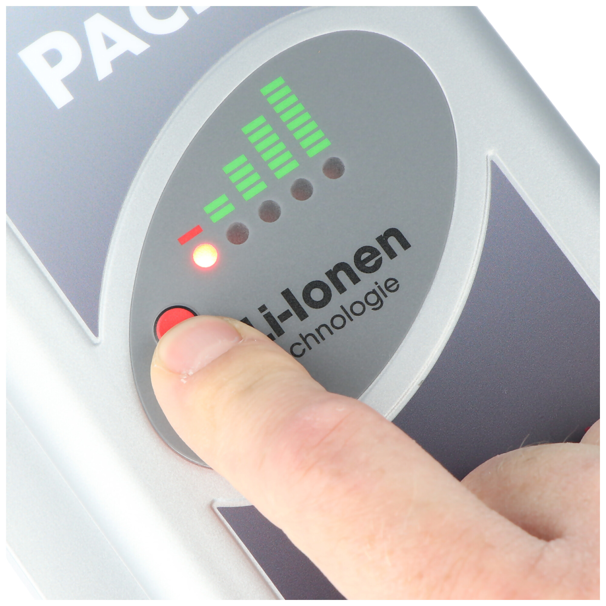 Eine Hand drückt auf eine rote Taste an einem Gerät. Grüne Balken und Lichter zeigen den Batteriestand an, mit einem roten Licht.
