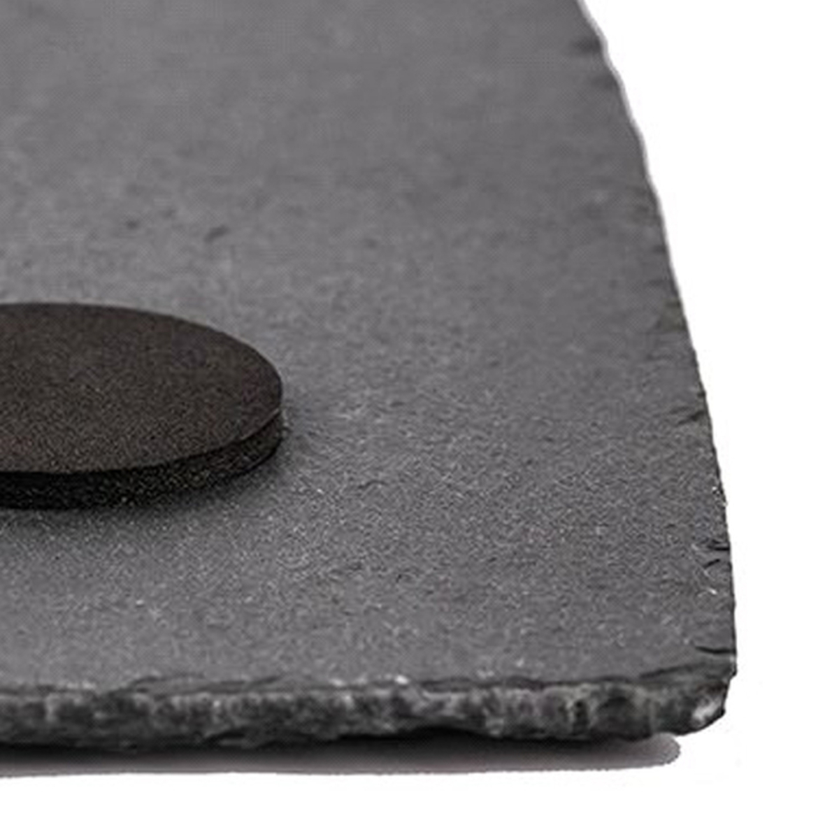 Primer plano de una pizarra gris con un pequeño posavasos negro redondo a la derecha.