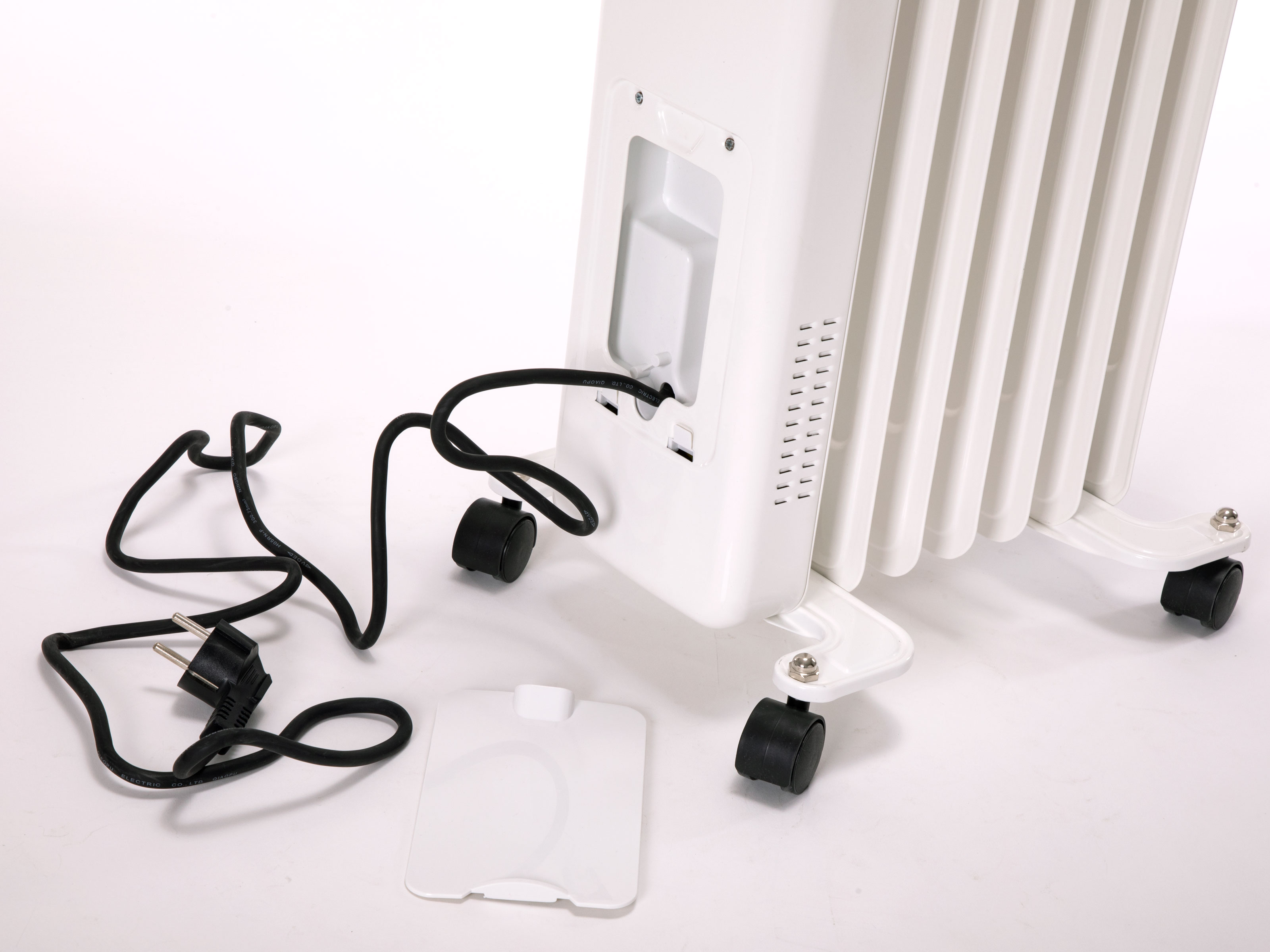 Weißer Ölradiator mit Kabel und Stecker. Eine weiße Abdeckung liegt vor der Heizung auf weißem Hintergrund.