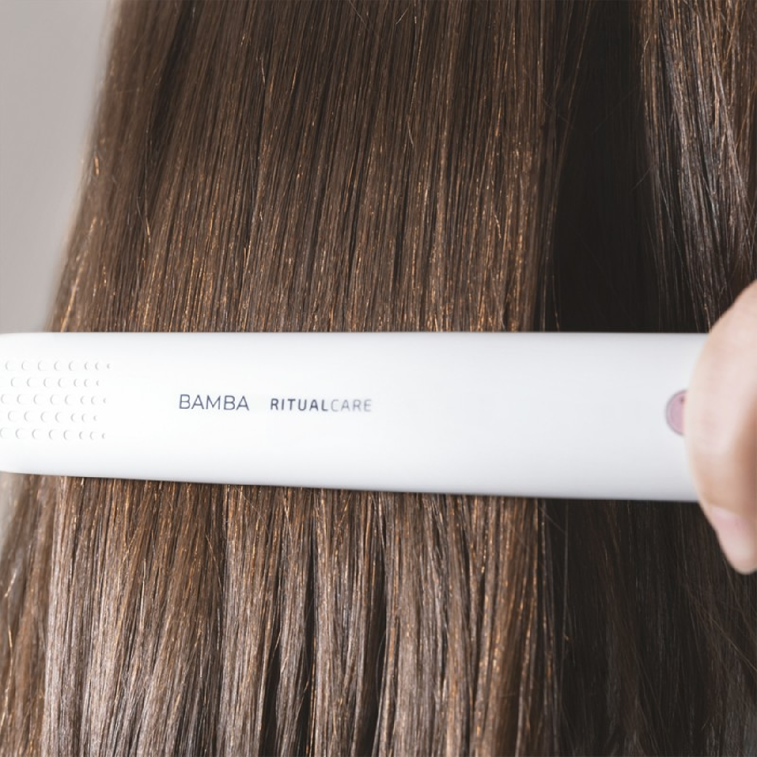 Una piastra per capelli bianca con la scritta 'BAMBA RITUALCARE', che liscia i capelli.
