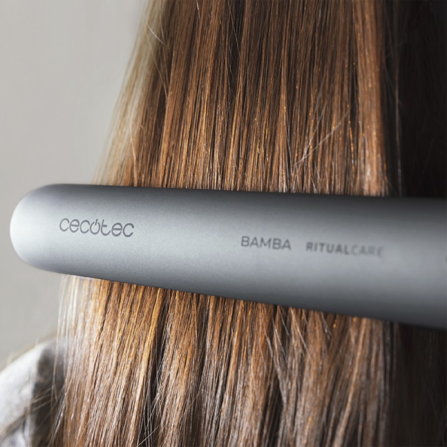 Una mujer usando una plancha de pelo Cecotec Bamba RitualCare en cabello castaño.