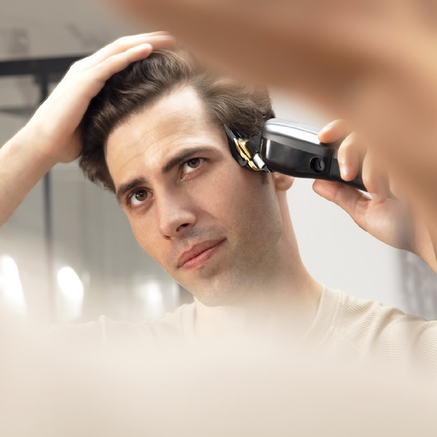 Un hombre se corta el pelo con una recortadora eléctrica frente a un espejo.
