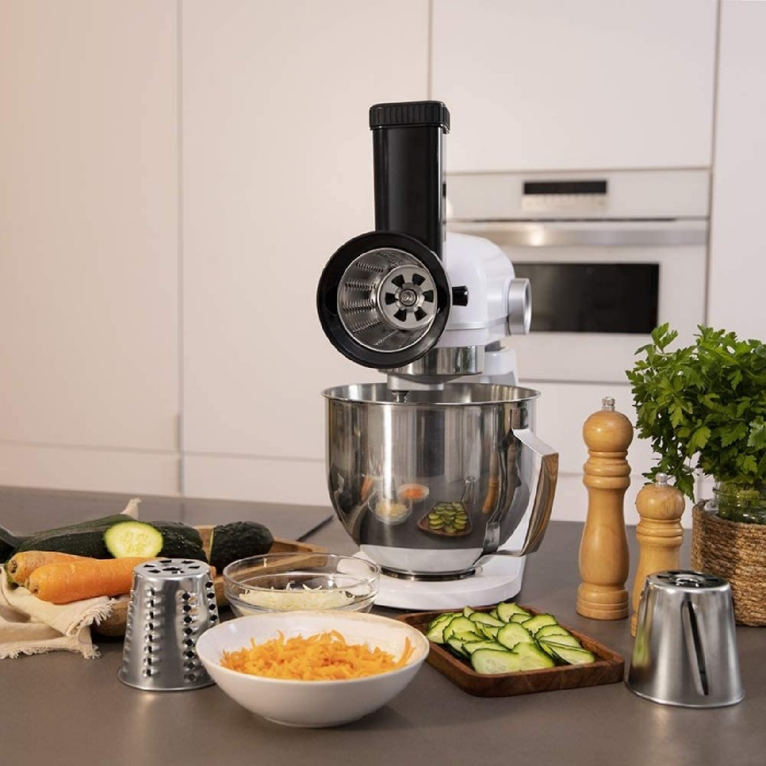 Biały mikser z przystawką do robota kuchennego; obok warzywa i ser.