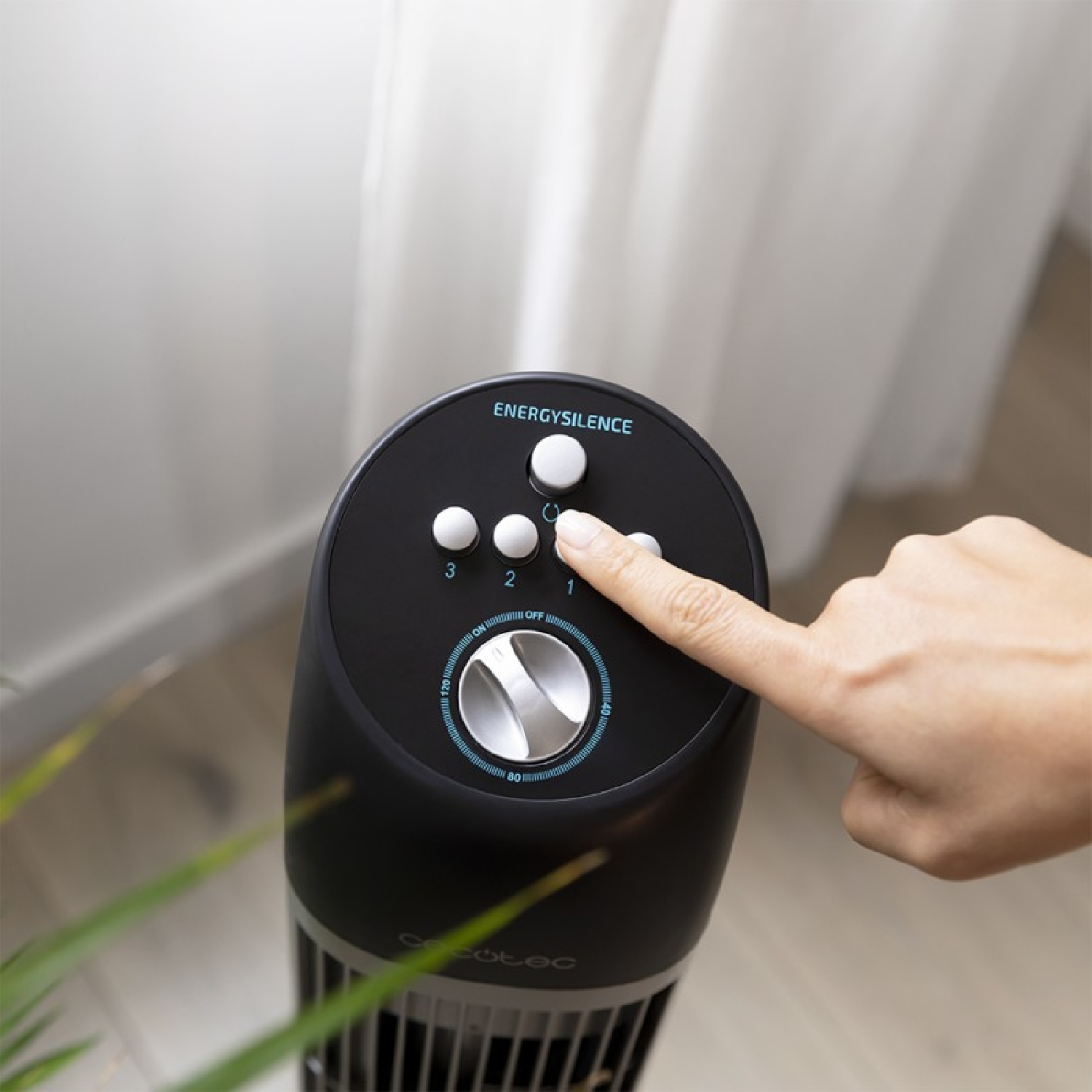 Palec naciska przycisk na czarnym wentylatorze ze słowem ENERGYSILENCE.