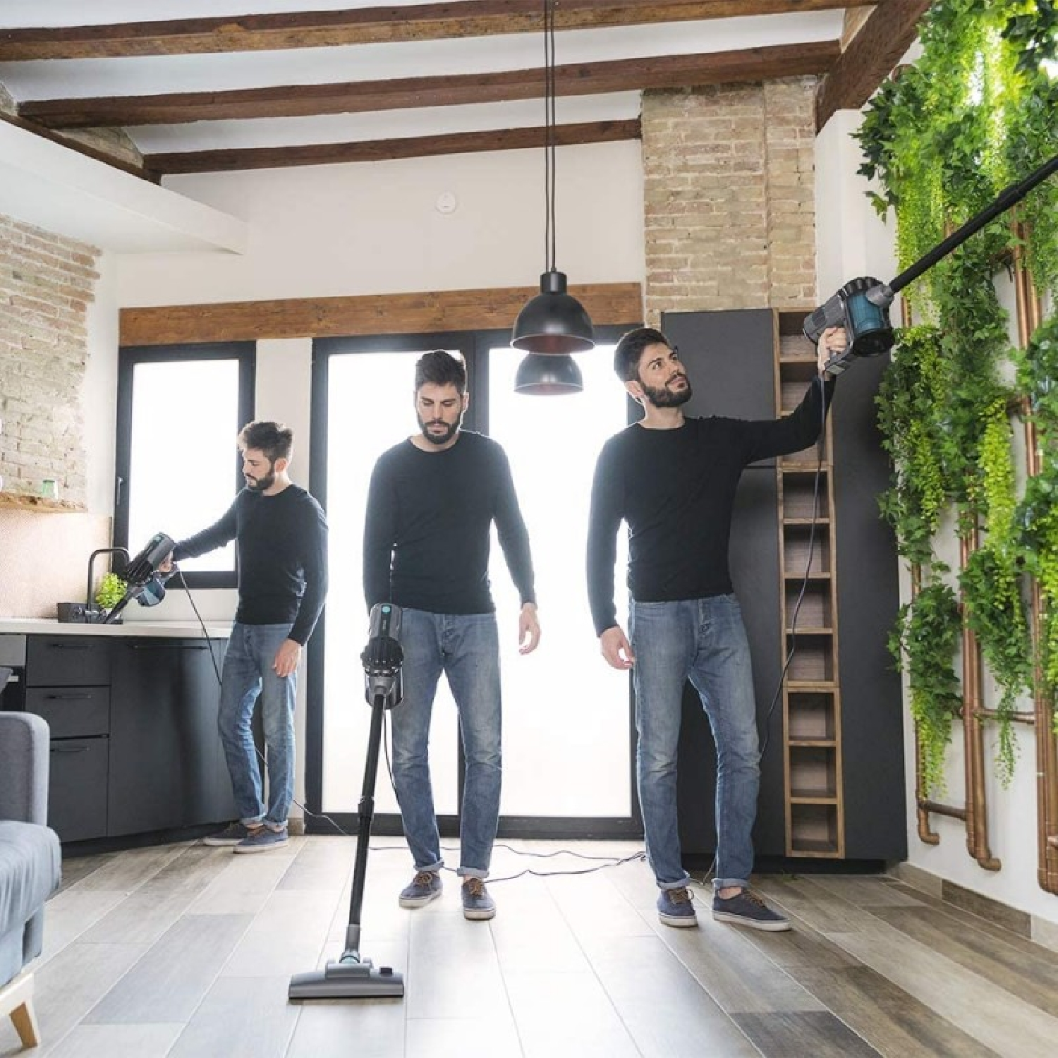 Three men vacuuming a room with a variety of vacuums and a plant wall backdrop.