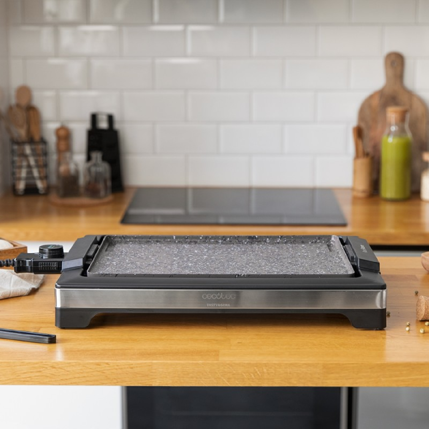 Ein elektrischer Grill auf einem Holztisch mit weißem Fliesen-Hintergrund.