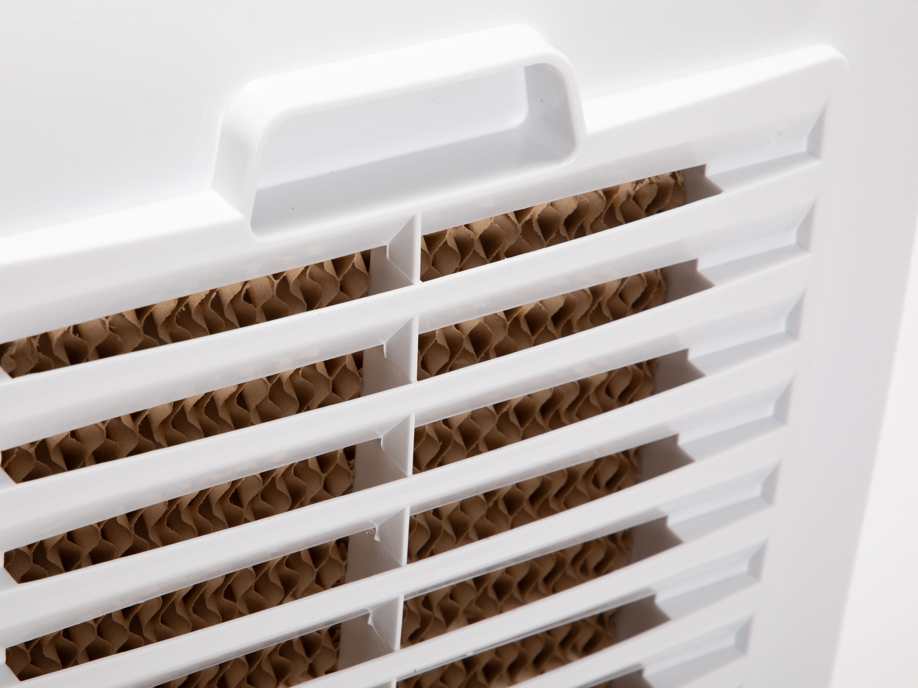 Ein weißer Klimaanlage mit weißen Gittern und braunem Papierfilter, Nahaufnahme.