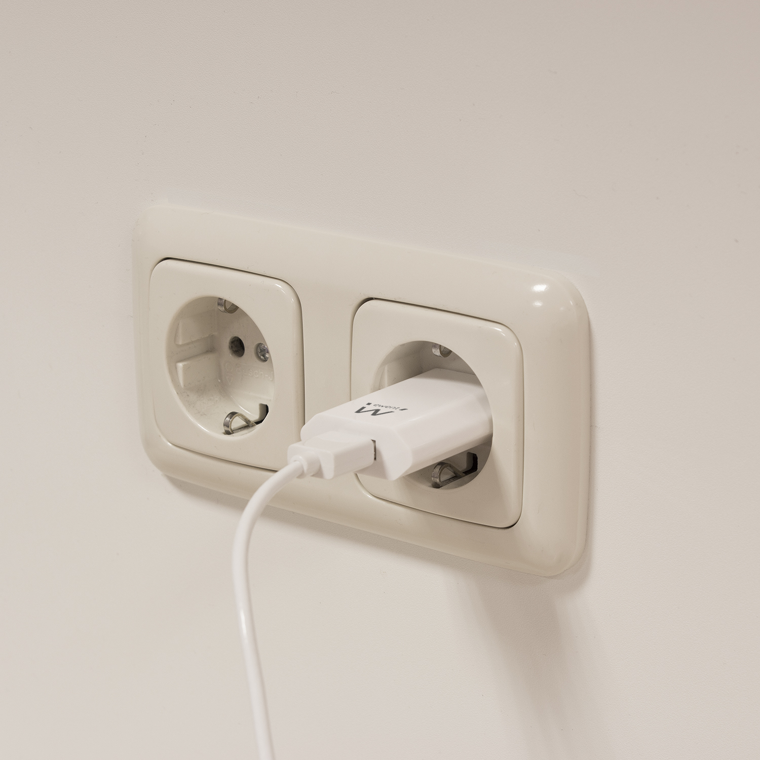 Due prese elettriche con un caricatore bianco collegato a una su un muro bianco.