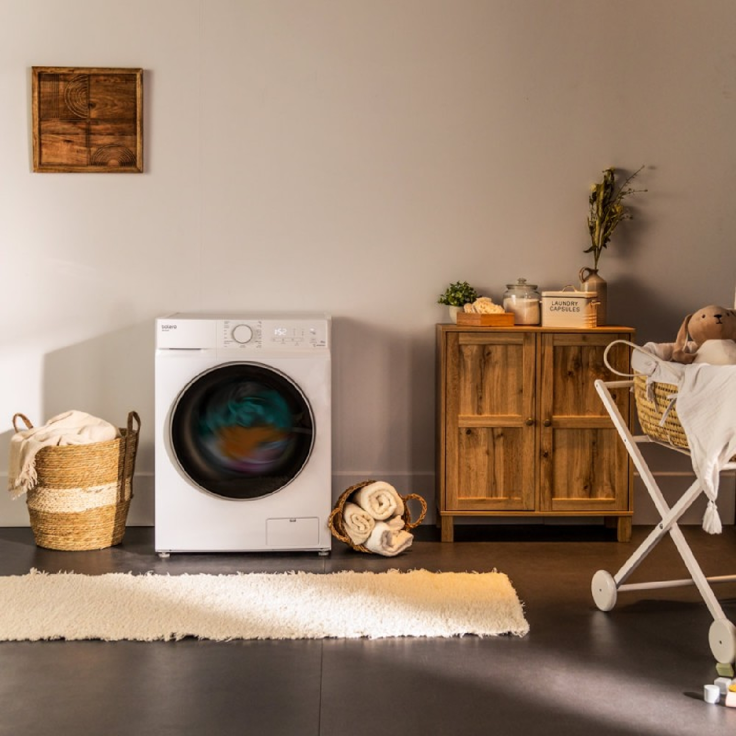 Una lavadora blanca con un ciclo de lavado en progreso, con una cesta de lavandería y un armario en una habitación.