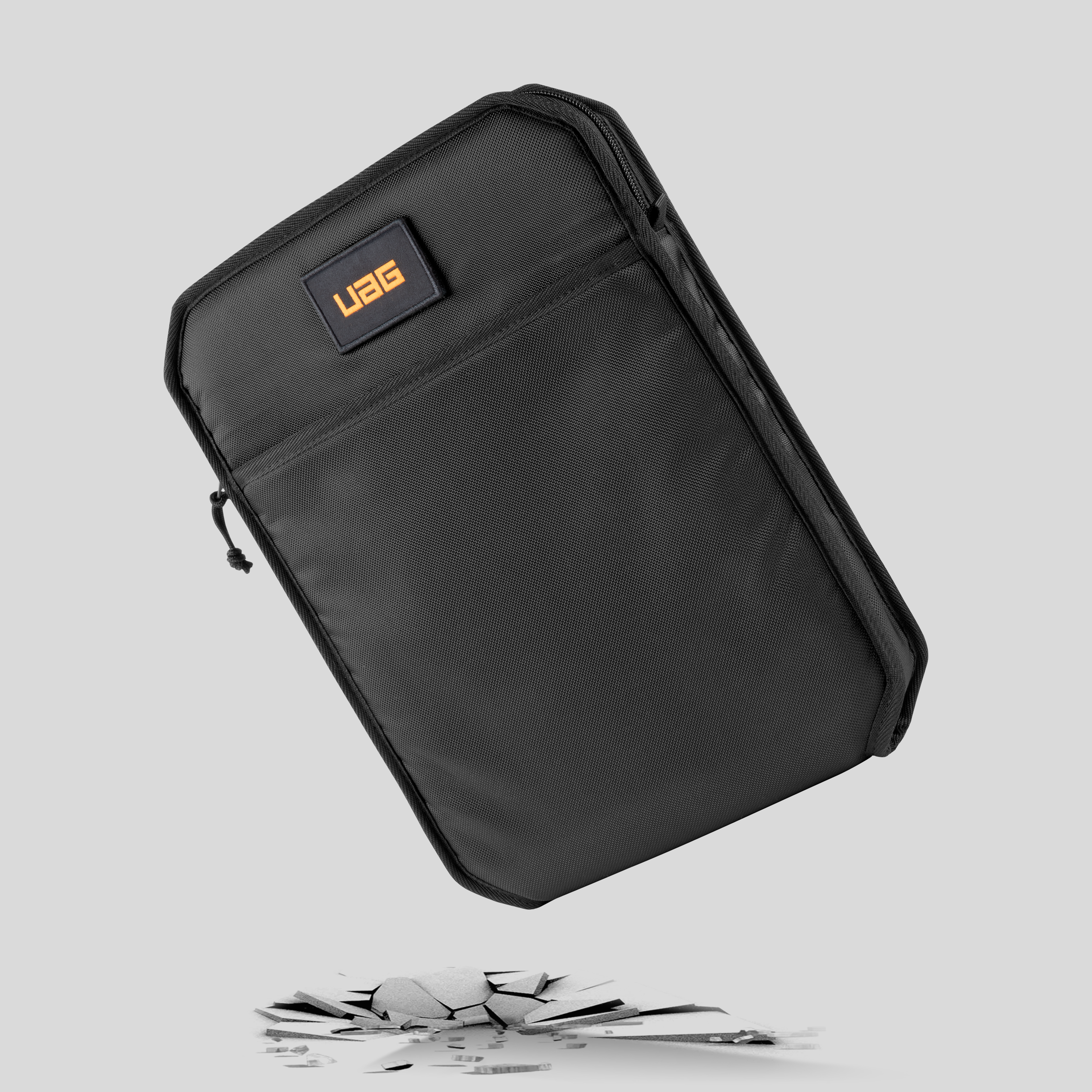 Schwarze UAG Tablet-Hülle fällt, mit zerbrochenem Boden darunter.