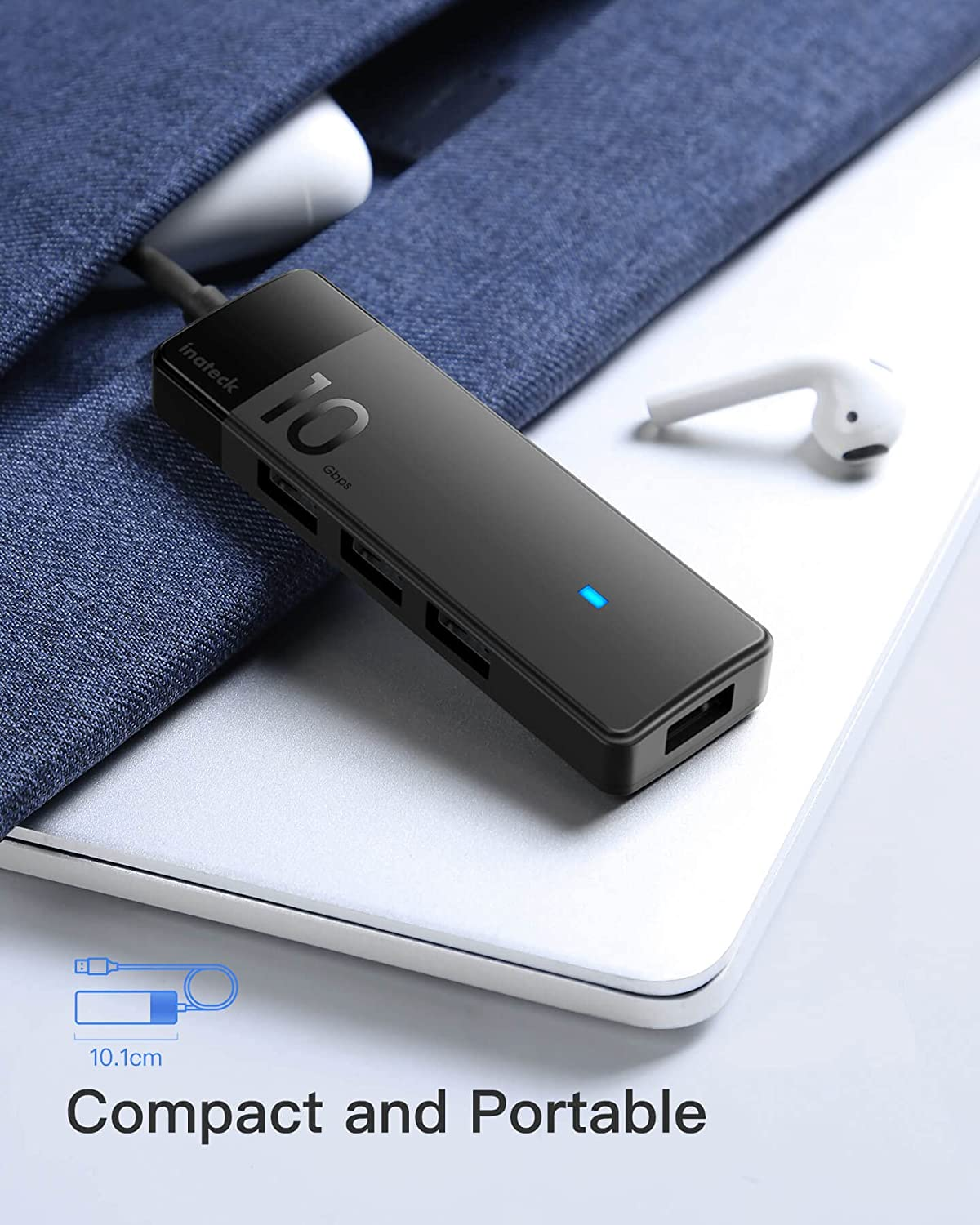 Concentrador USB negro con múltiples puertos y una laptop blanca con auriculares.