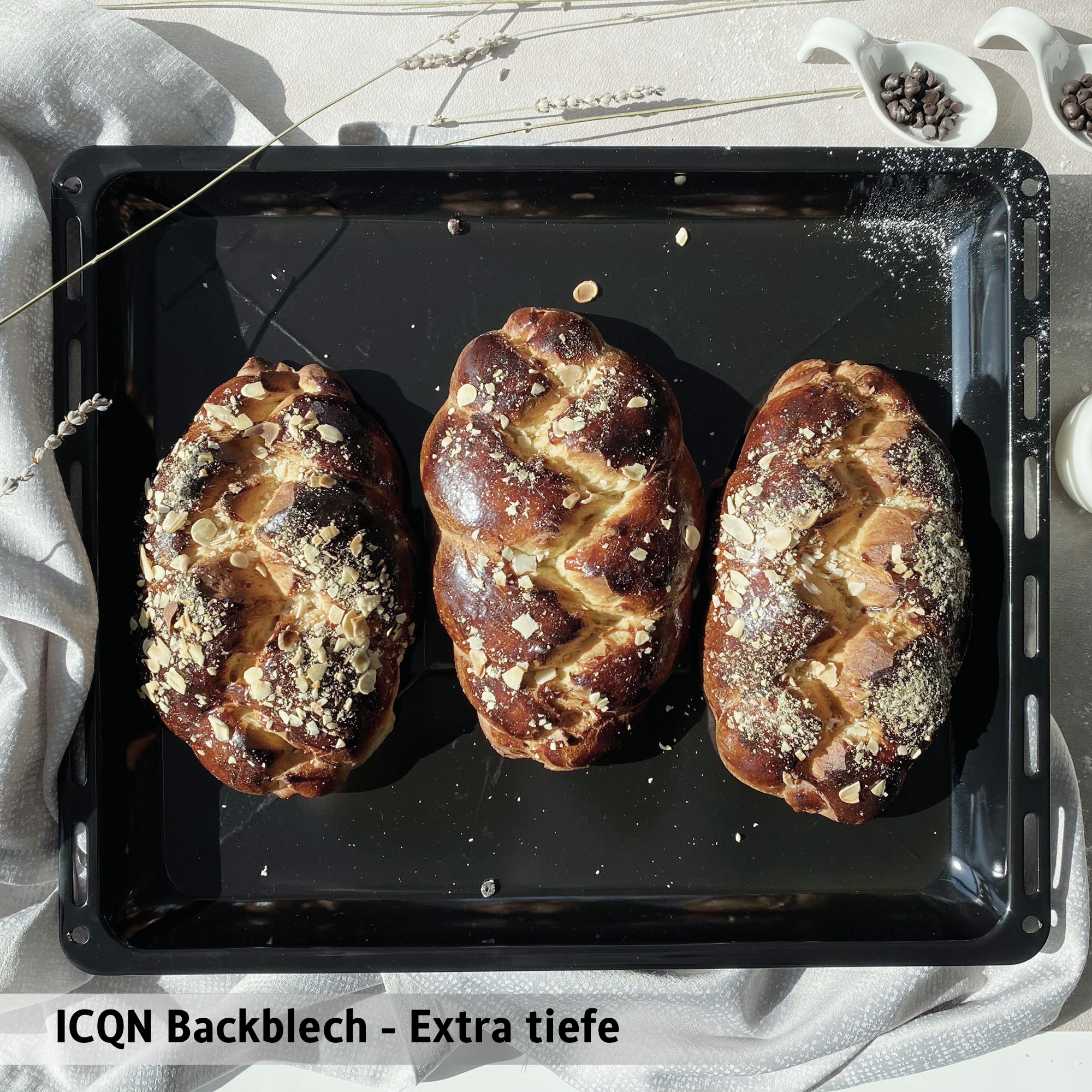 Drei geflochtene Brote mit Mandeln auf einem Backblech, natürliche Beleuchtung.