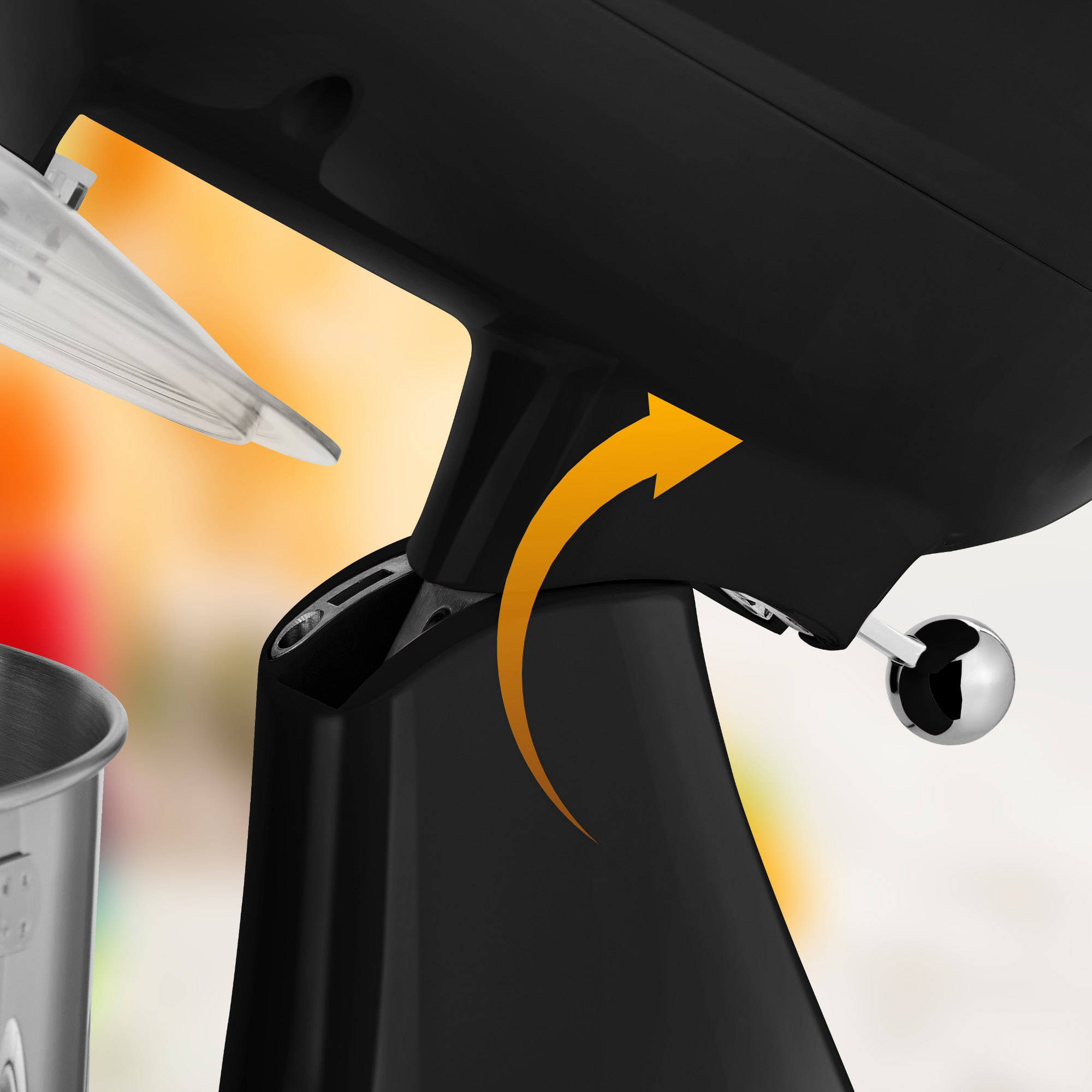 Schwarzer Mixerfuß mit orangefarbenem Pfeil. Mixer teilweise sichtbar, silberne Schüssel.