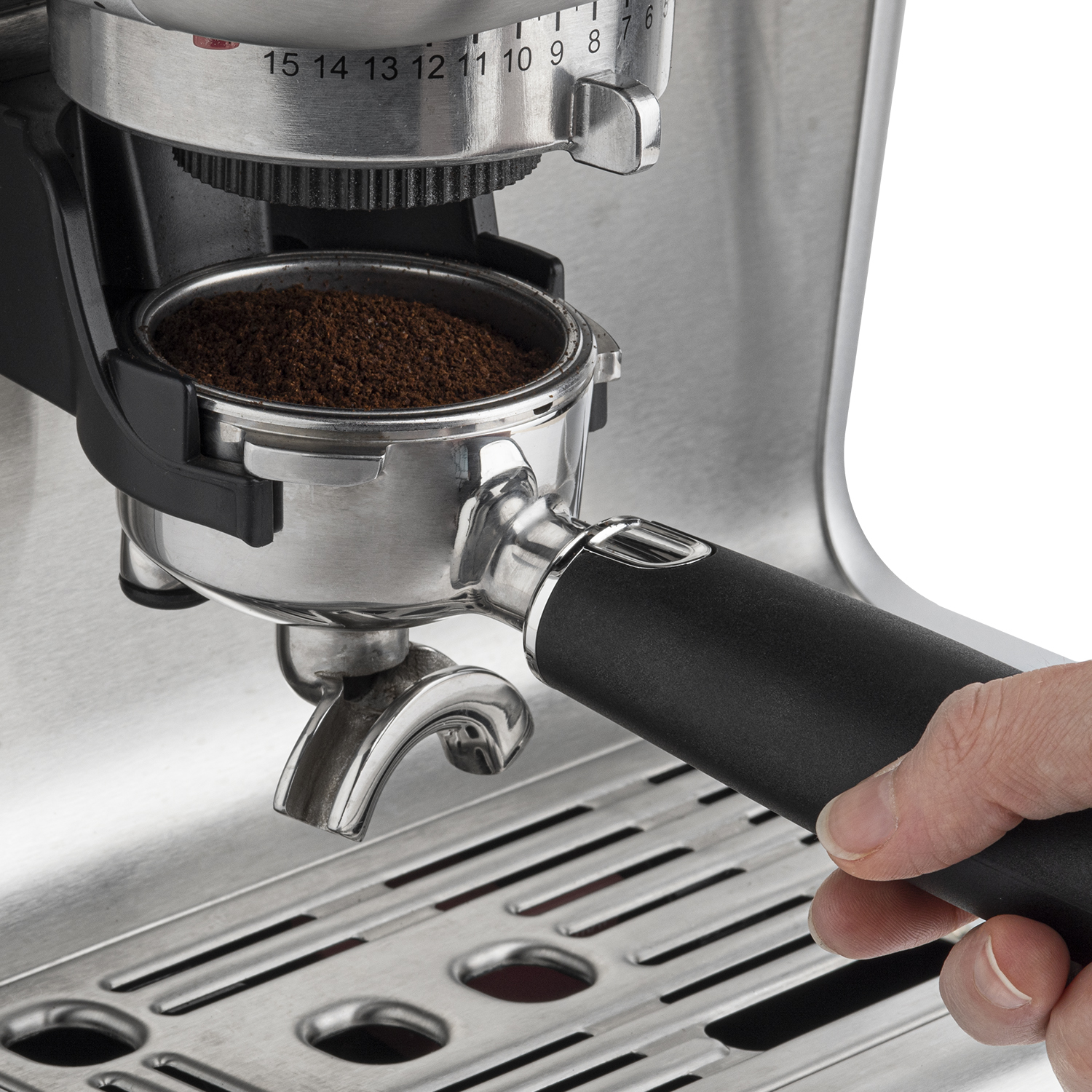 Una macchina per caffè espresso. Una mano tiene il portafiltro con caffè macinato.