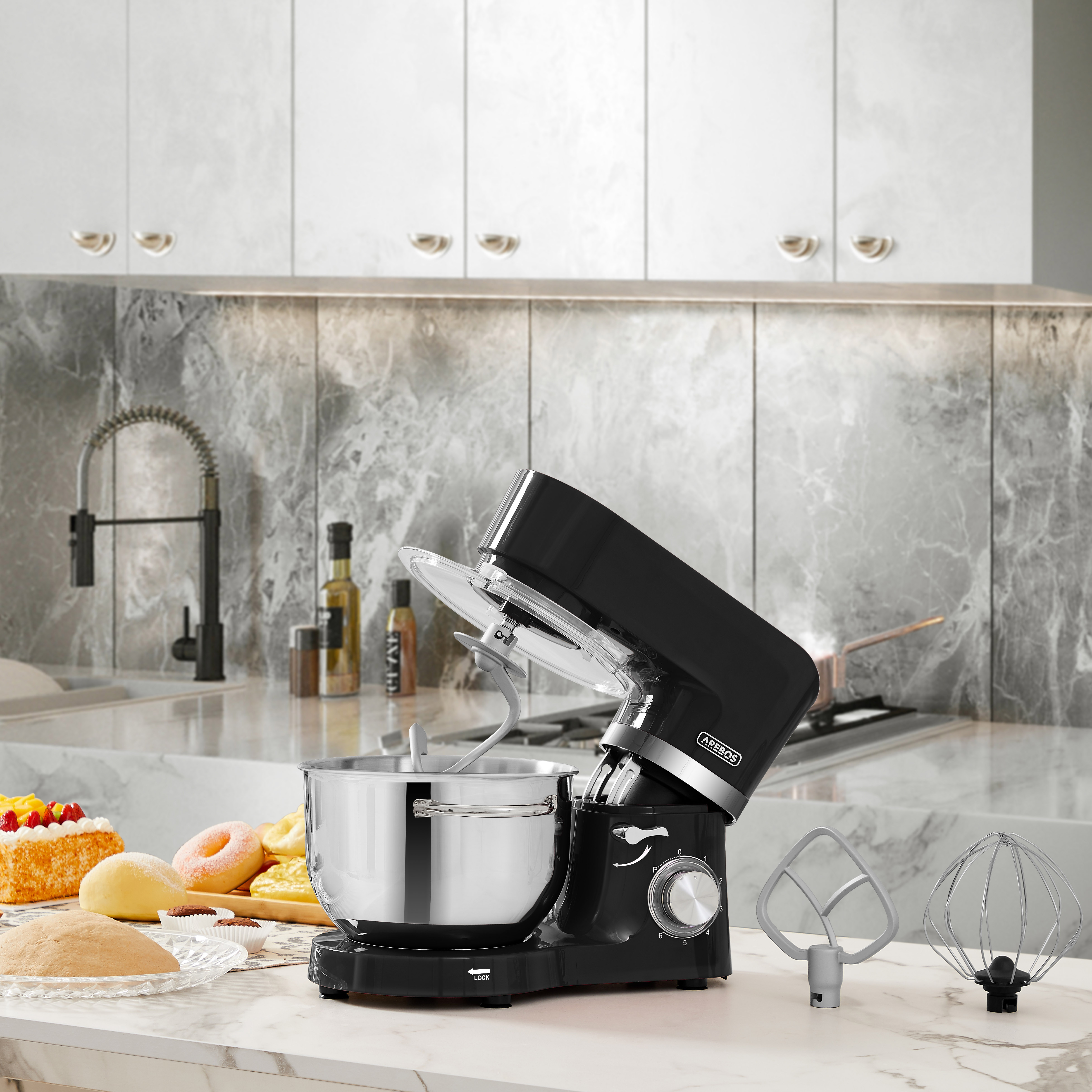 Schwarzer Küchenmixer mit Aufsätzen, auf Marmorarbeitsplatte.