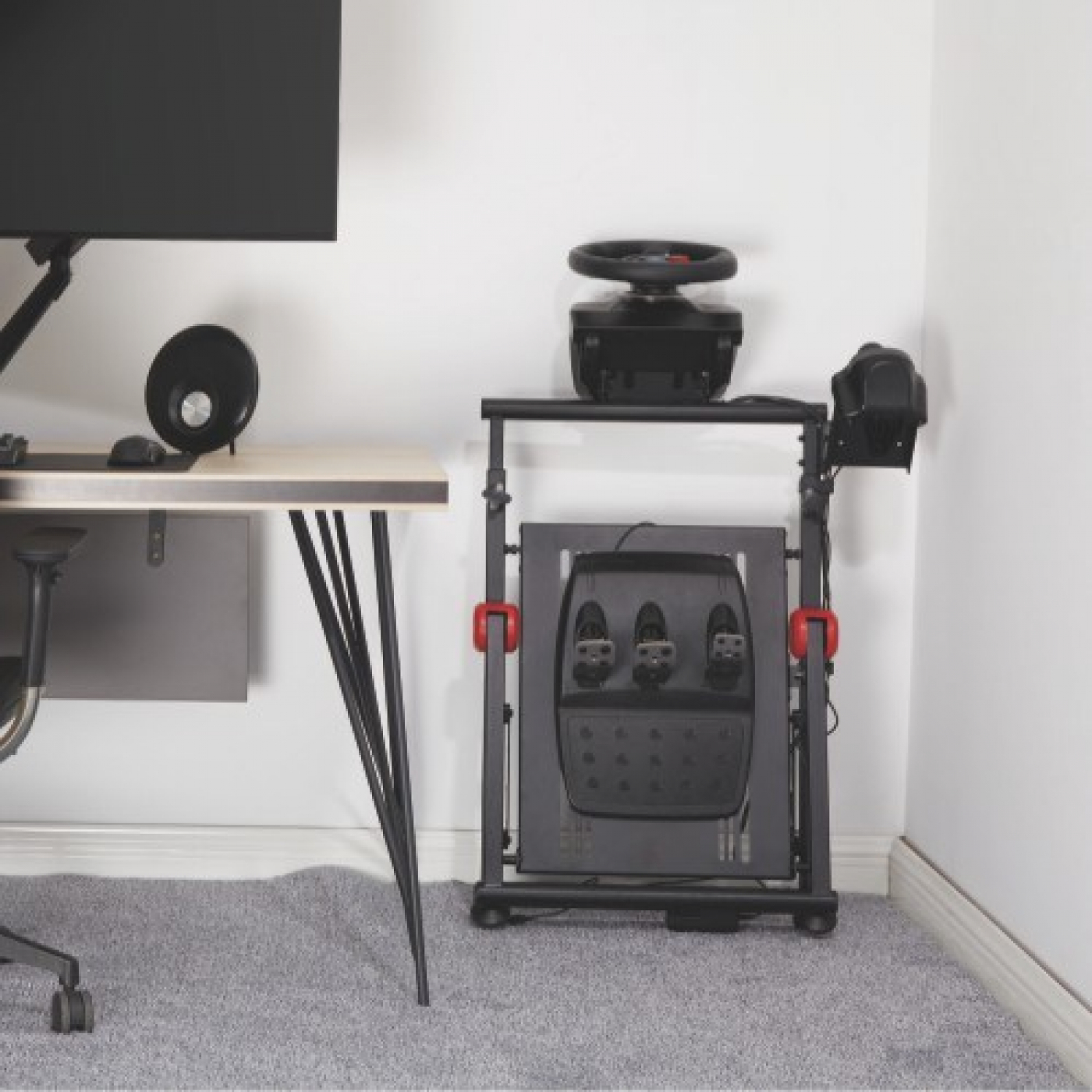 Gaming-Setup mit Schreibtisch, Monitor, Lautsprechern und einem Rennspielsimulator.