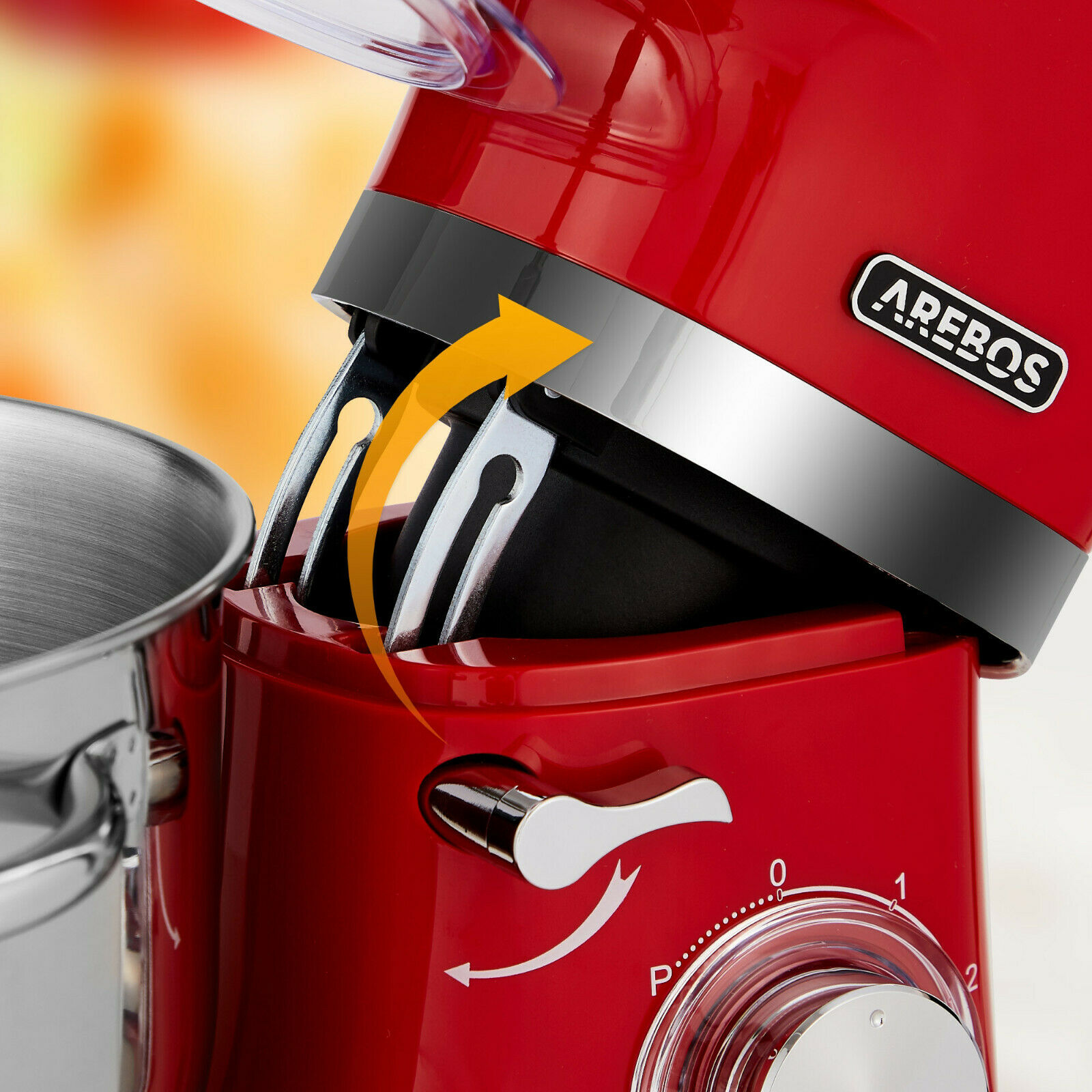 Ein roter Küchenmixer mit einer Edelstahlschüssel. Ein Pfeil zeigt auf den Mechanismus des Mixers.