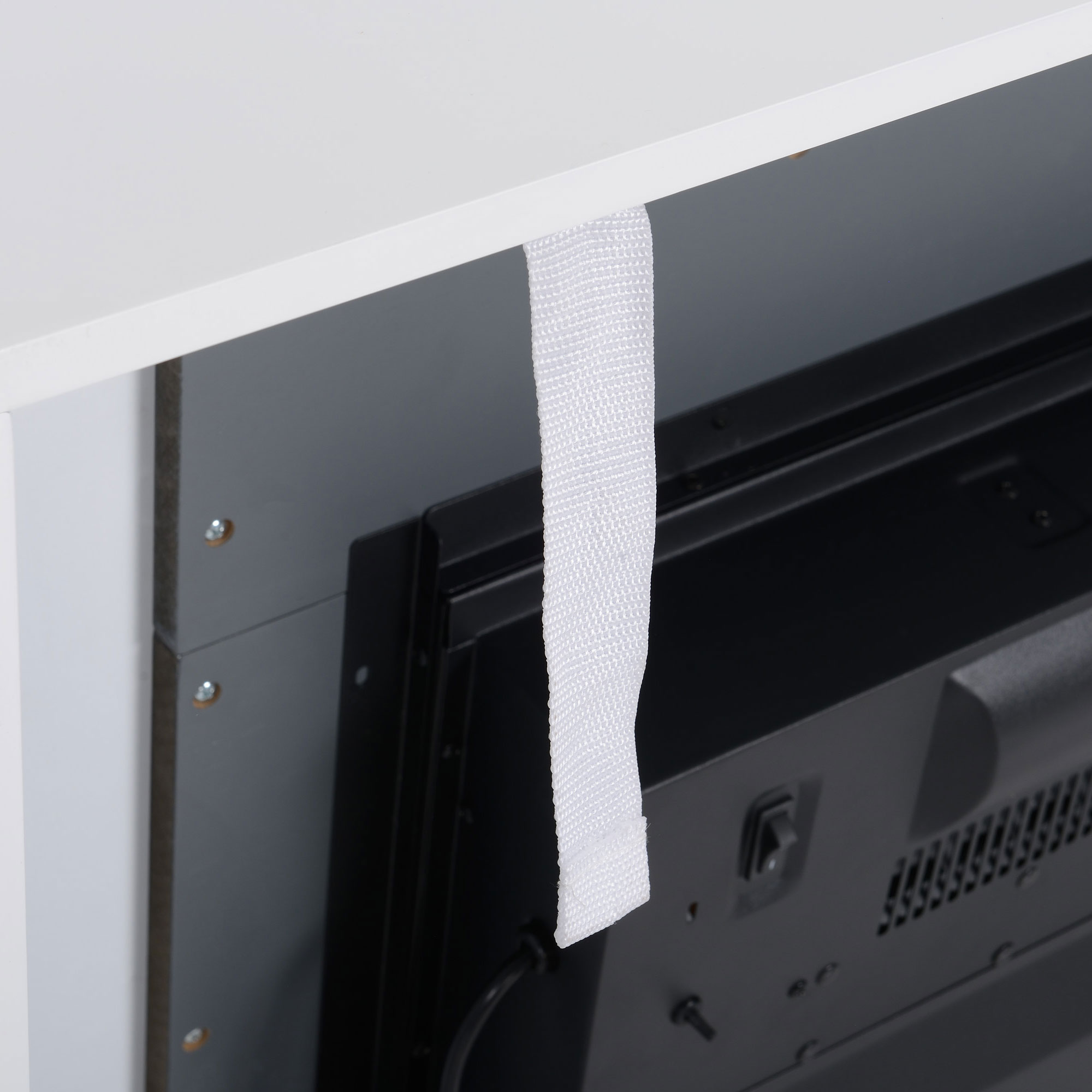 Un mueble de TV blanco con un televisor negro. Una correa blanca cuelga de la parte superior del mueble.