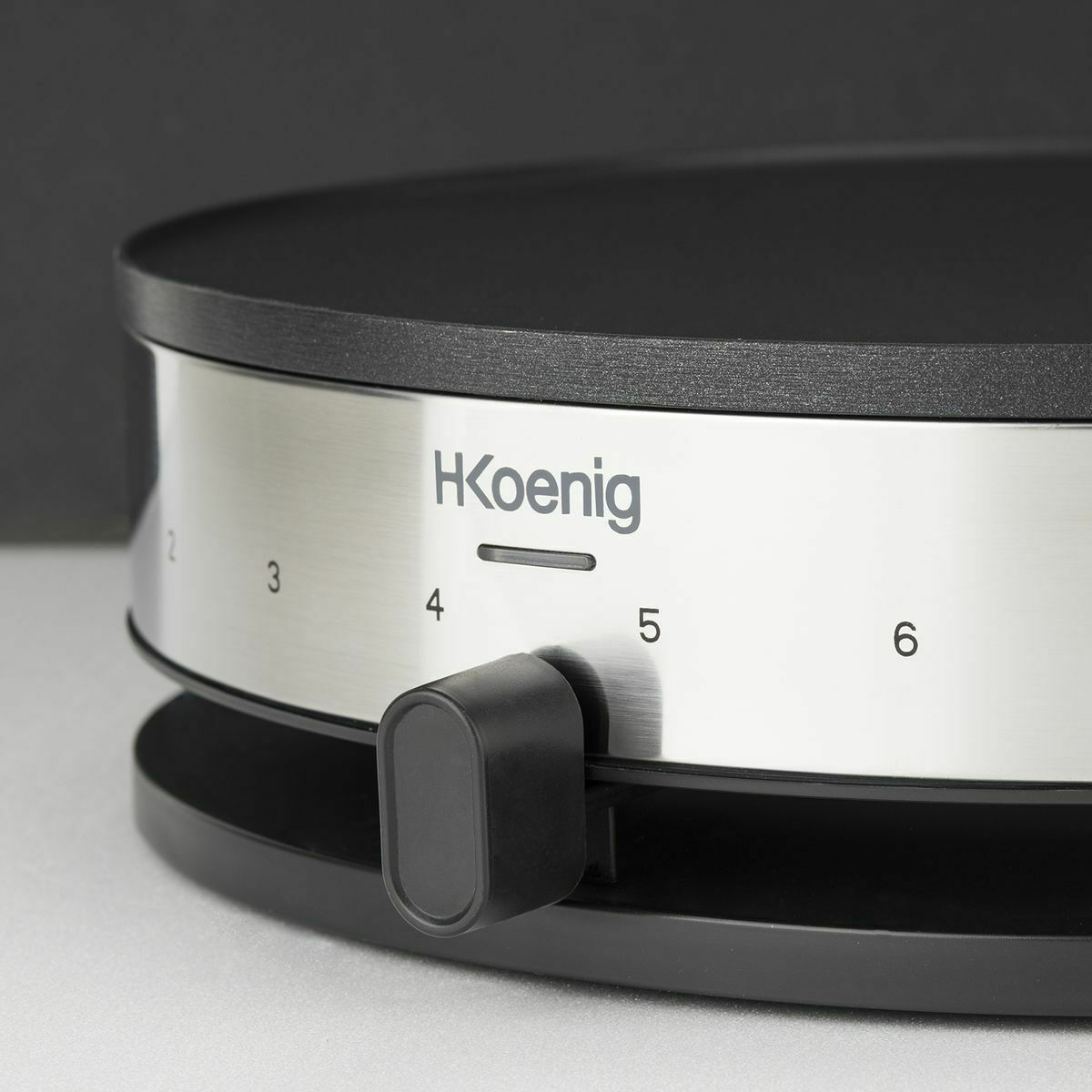 Zbliżenie srebrno-czarnego urządzenia z pokrętłem z cyframi od 2 do 6. Logo Hkoenig.