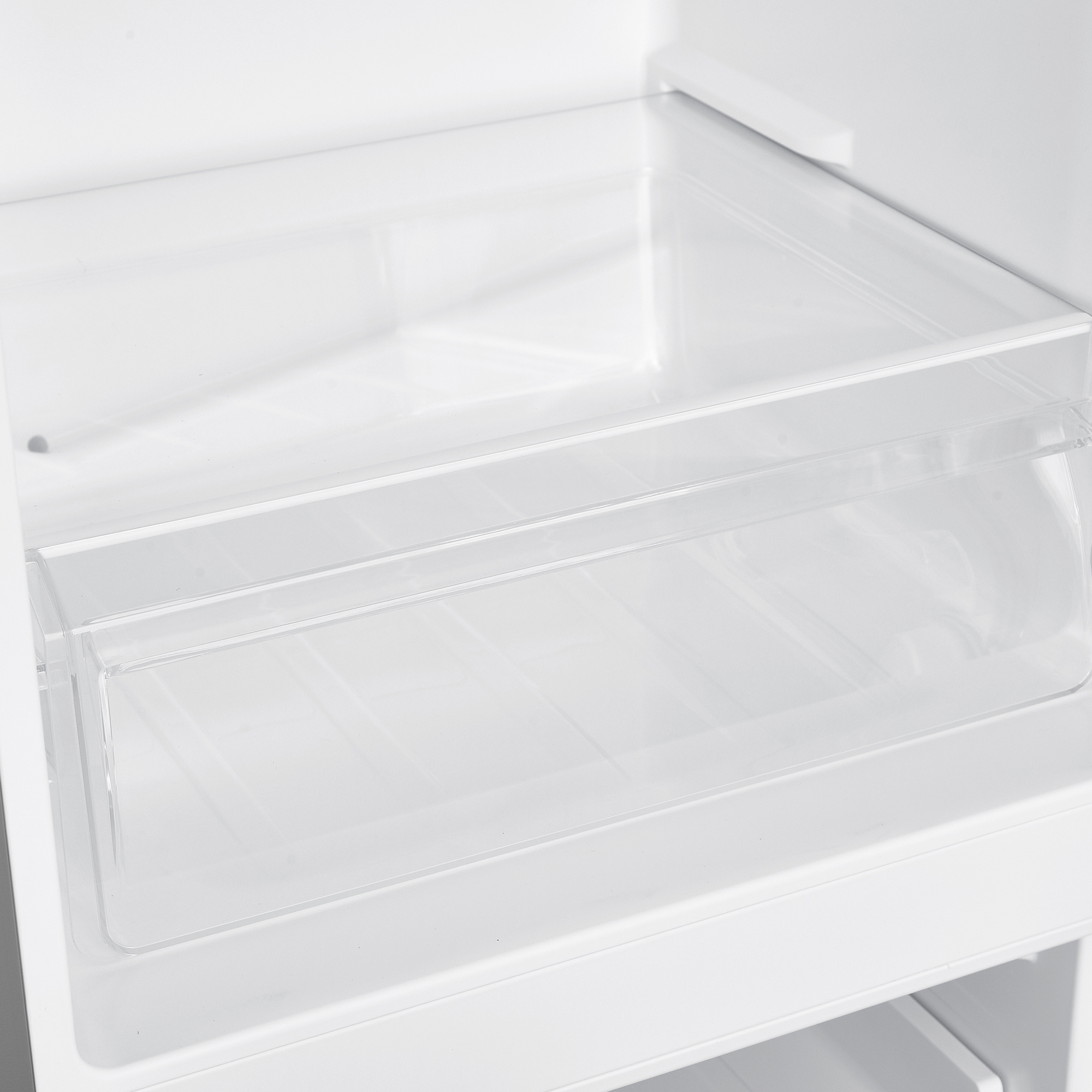 In einem weißen Kühlschrank ist ein durchsichtiges Kunststoffregal zu sehen.