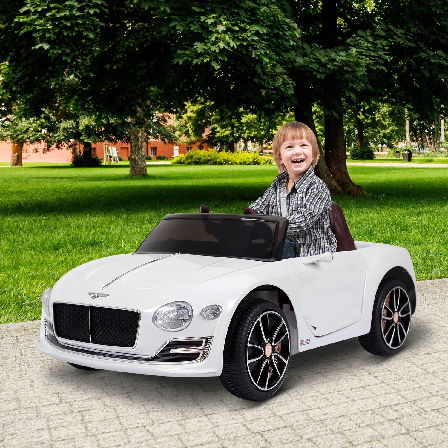 Un niño pequeño sonríe mientras conduce un coche de juguete blanco al aire libre en un día soleado.
