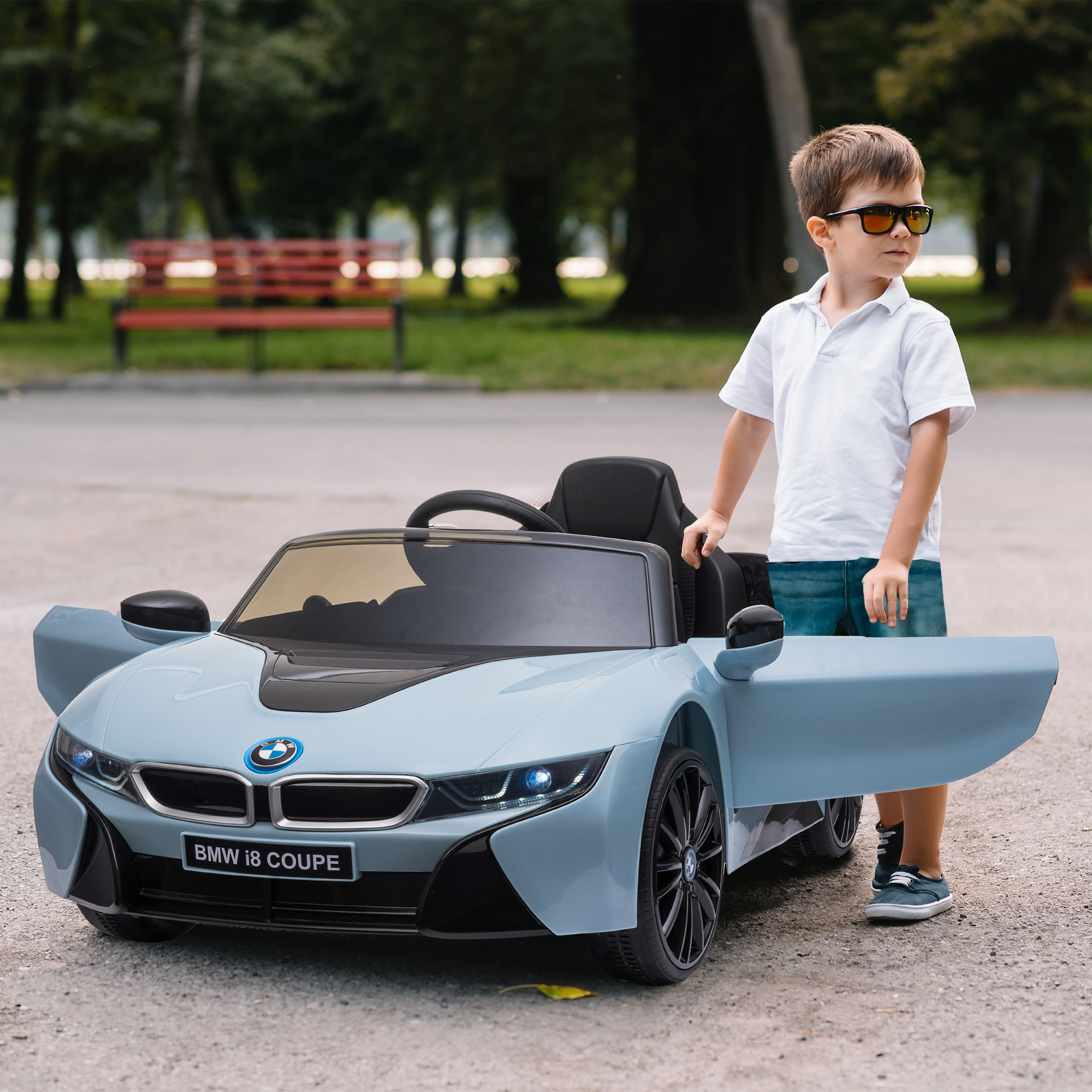 Un bambino accanto a una macchinina BMW i8 coupe azzurra con la portiera aperta.