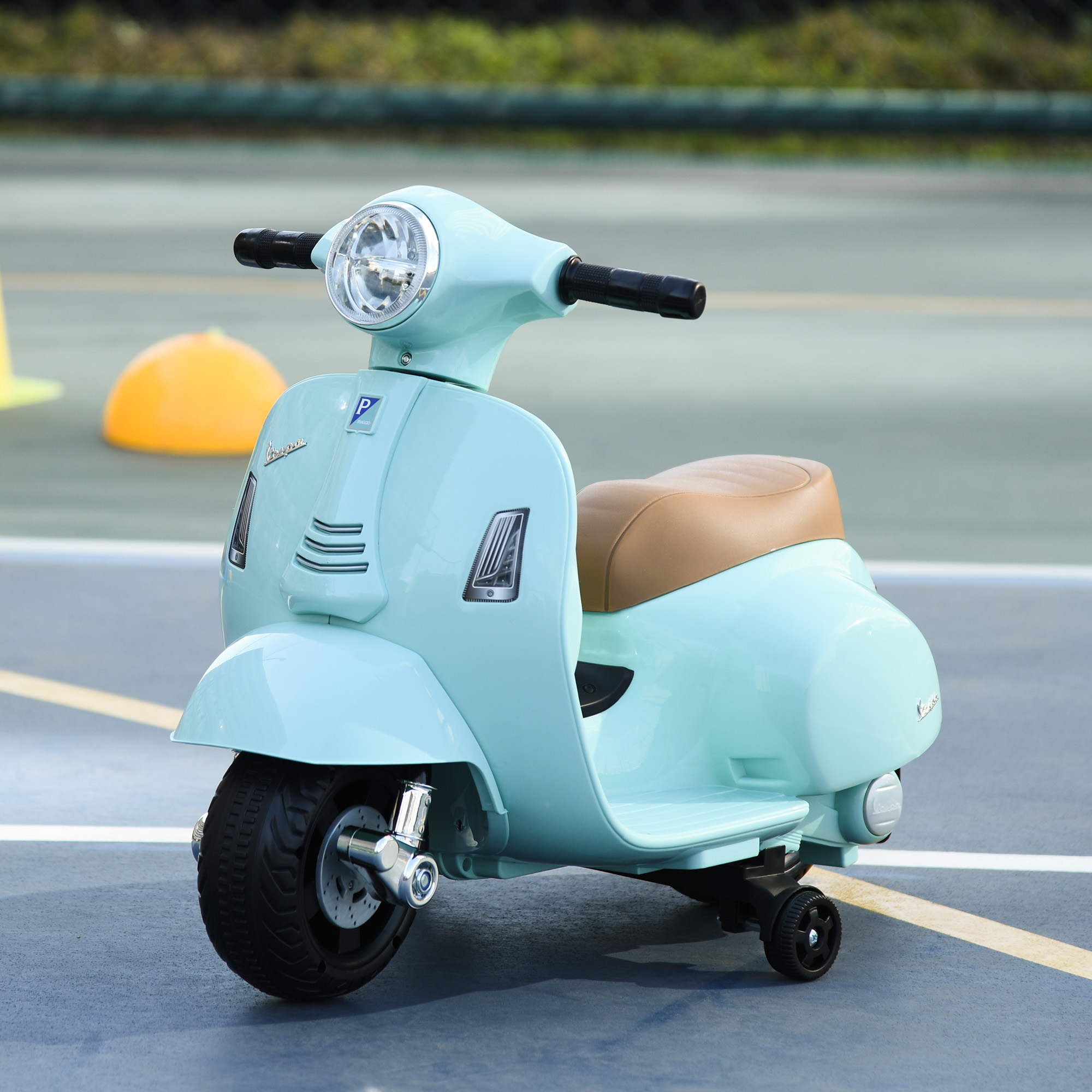 Un motorino giocattolo azzurro con un sedile marrone e una piccola ruota posteriore. Lo scooter è su un campo.