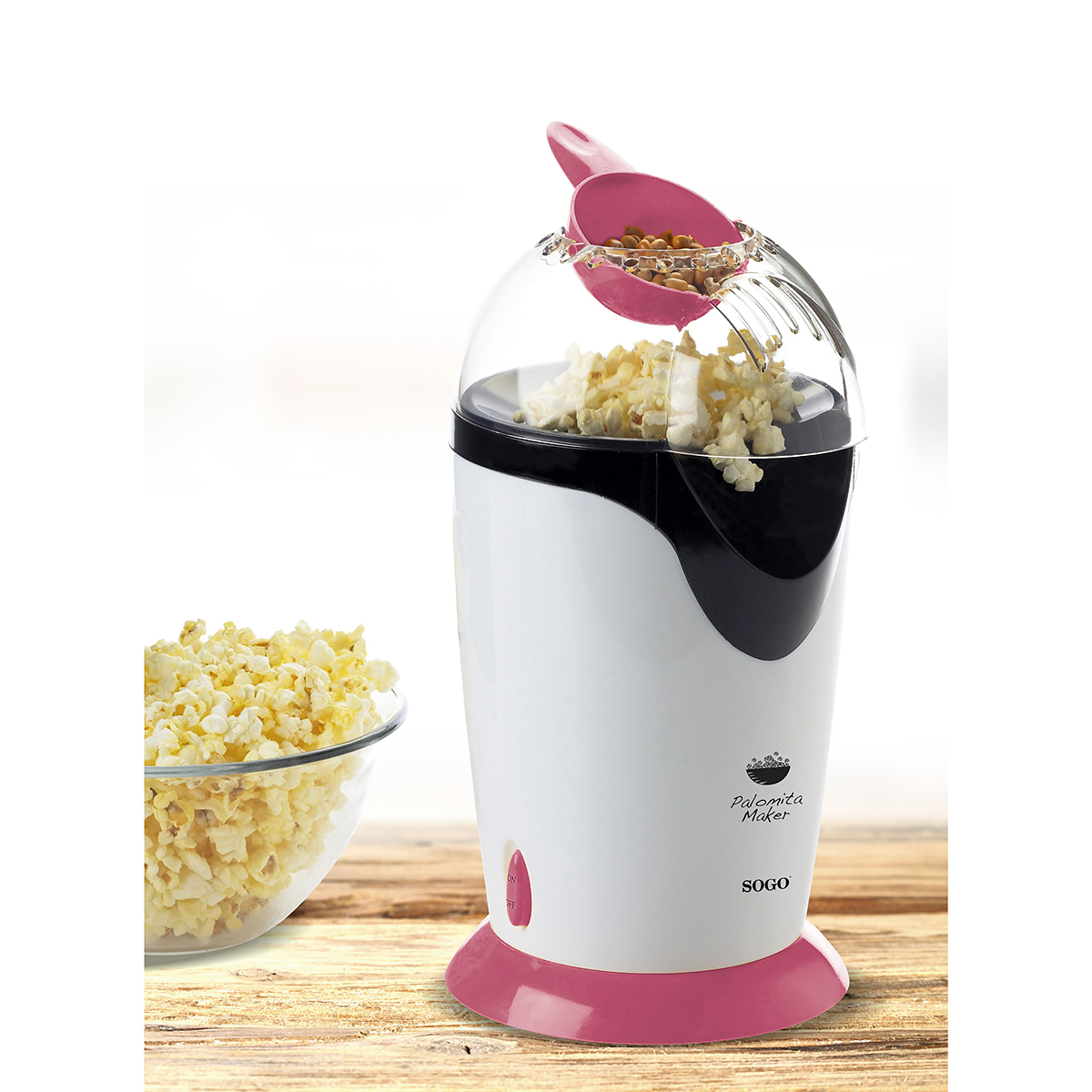 Máquina de palomitas con palomitas y un cuenco de palomitas. La máquina es rosa y blanca.