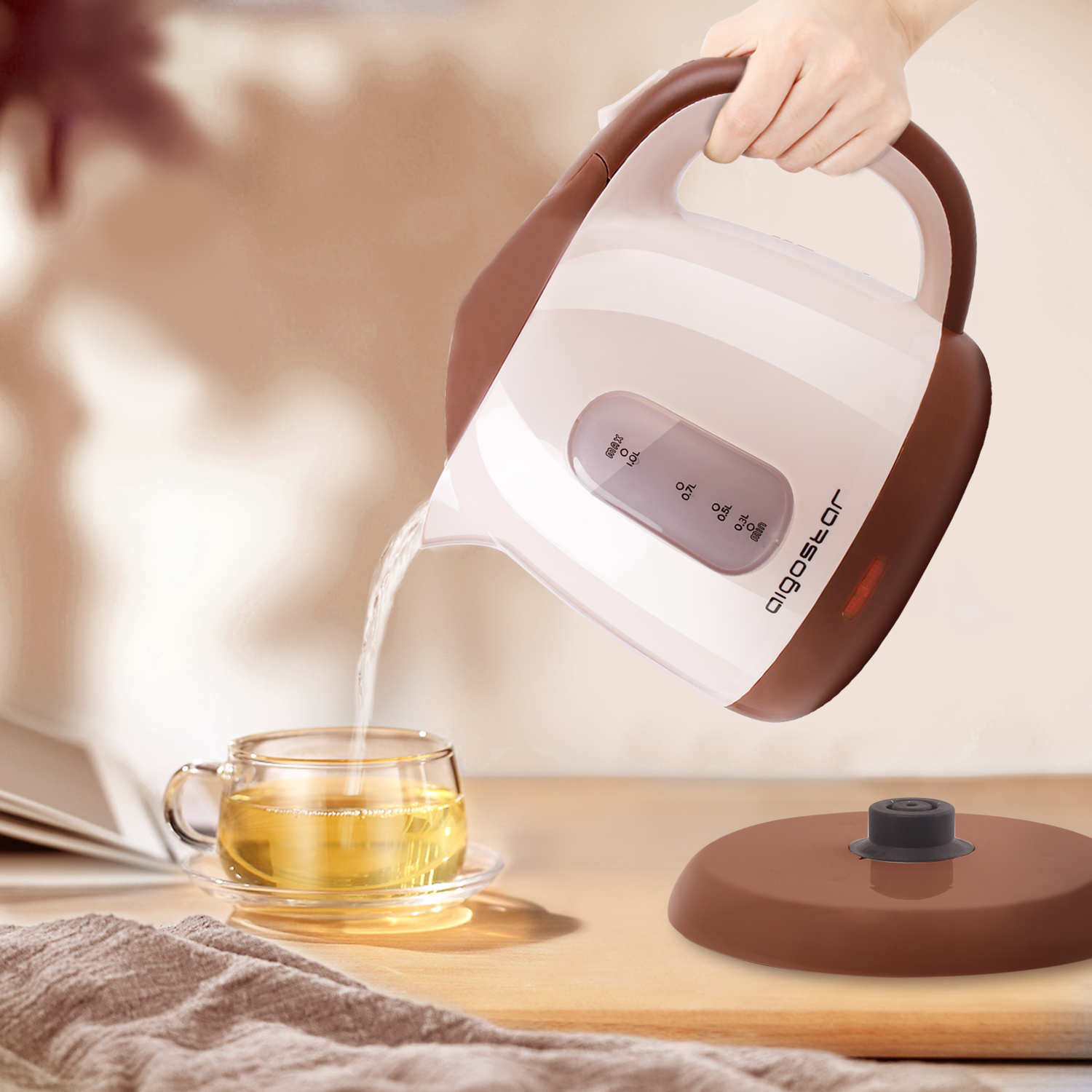 Un bollitore elettrico bianco e marrone versa acqua in una tazza di vetro.