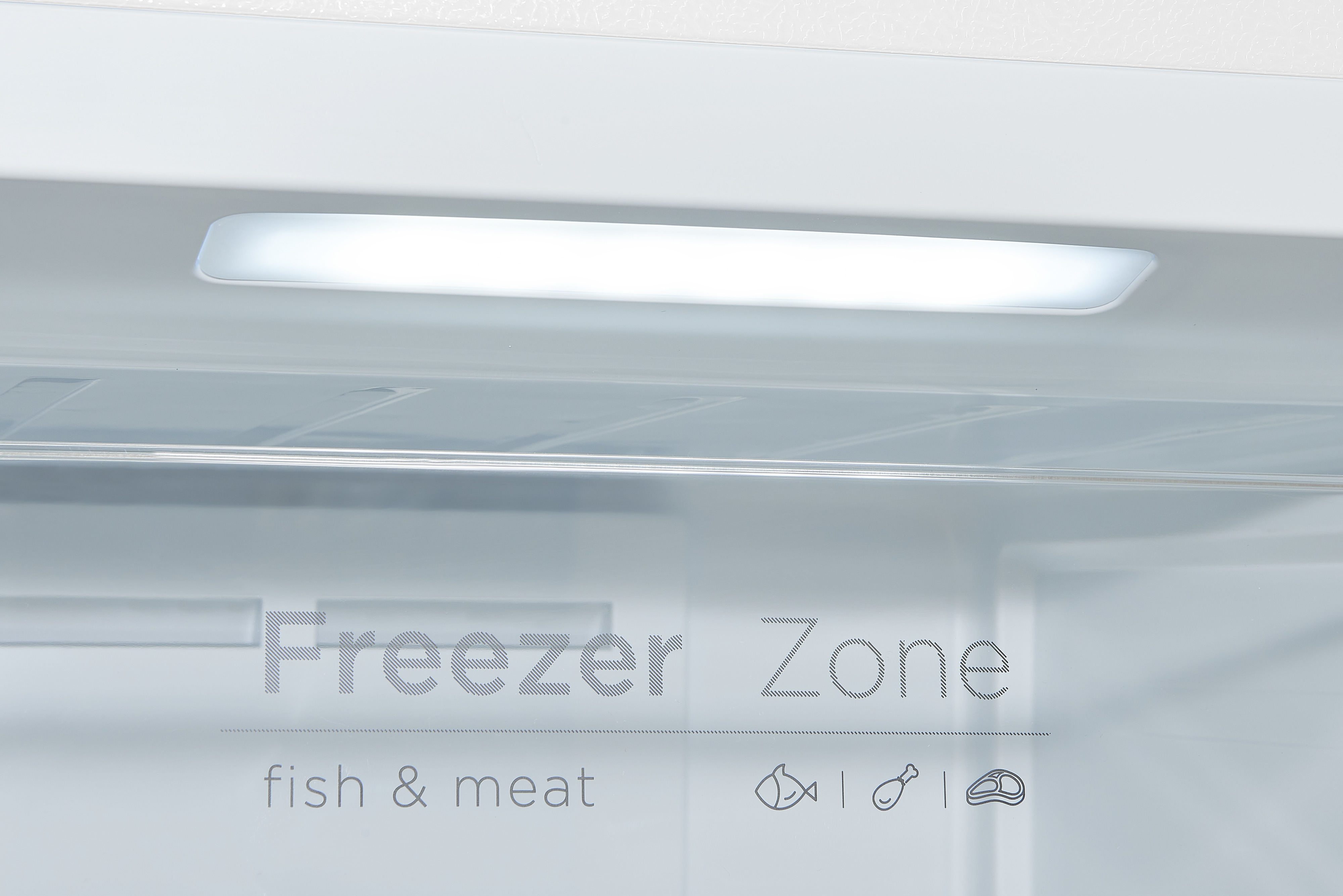 Im Inneren eines Gefrierschranks mit hellem Licht und Text: Gefrierzone, Fisch & Fleisch.