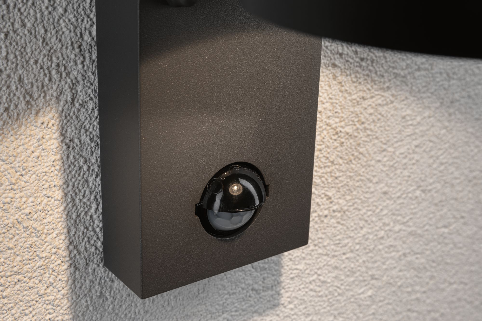 Zbliżenie czujnika ruchu na teksturowanej ścianie.