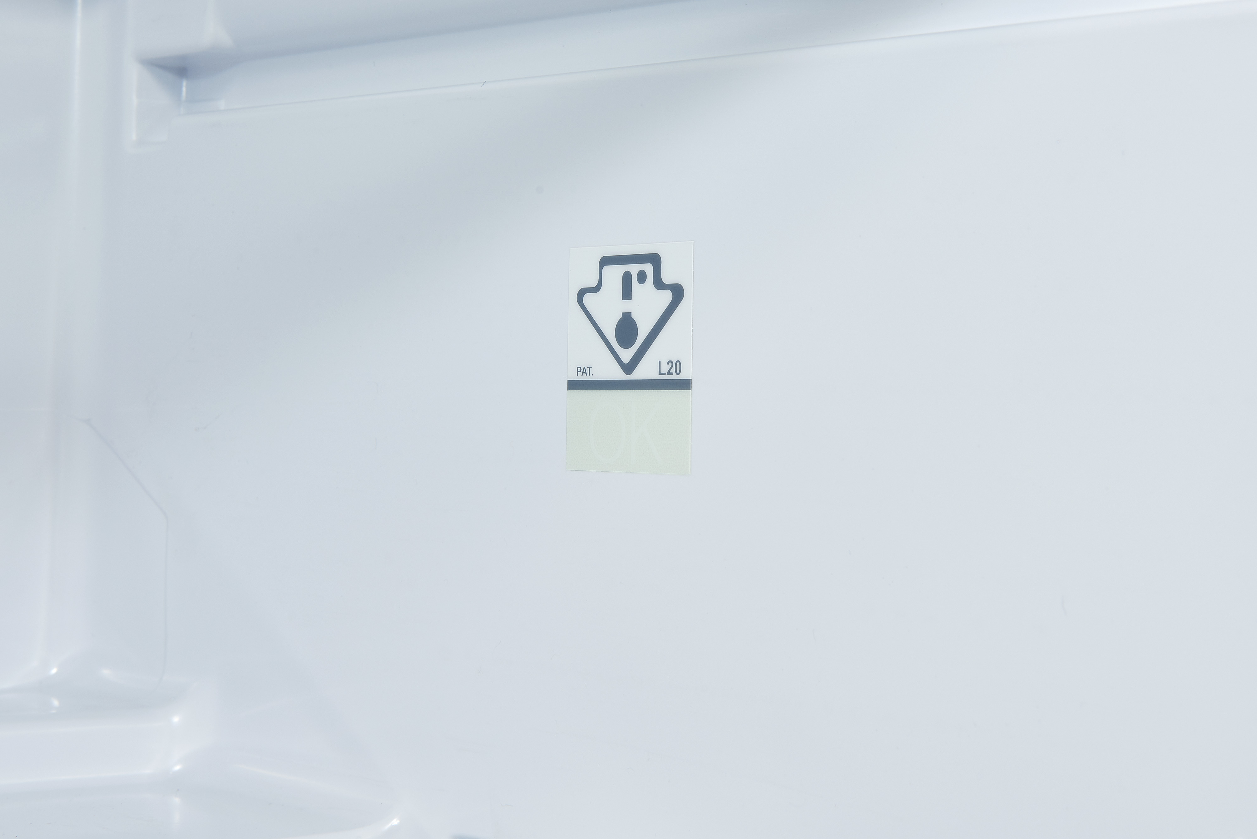 White refrigerator interior. A label with a warning symbol and text is visible.