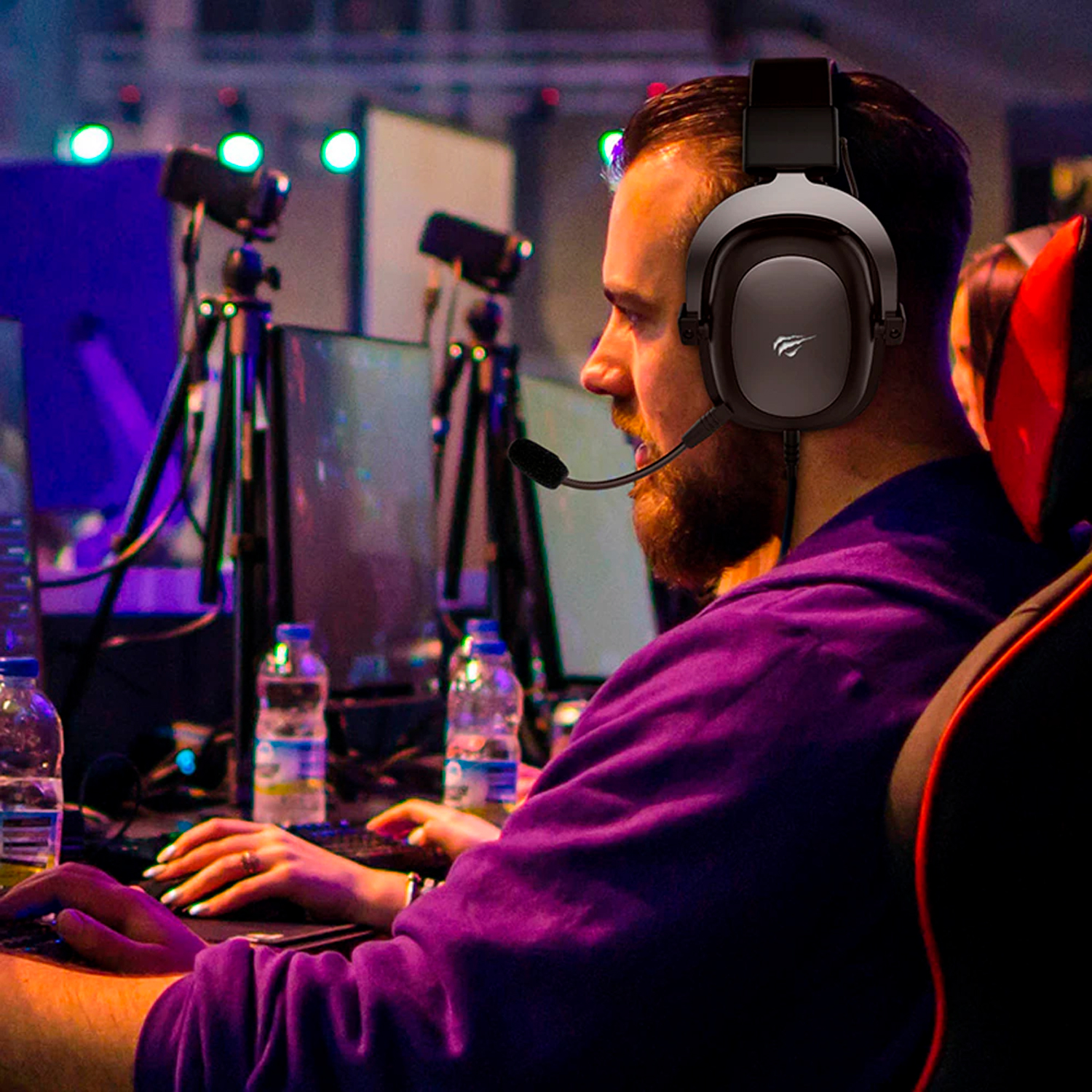 Mężczyzna w zestawie słuchawkowym do gier z mikrofonem i siedzący, patrzący na ekran komputera. Rozmyte tło.